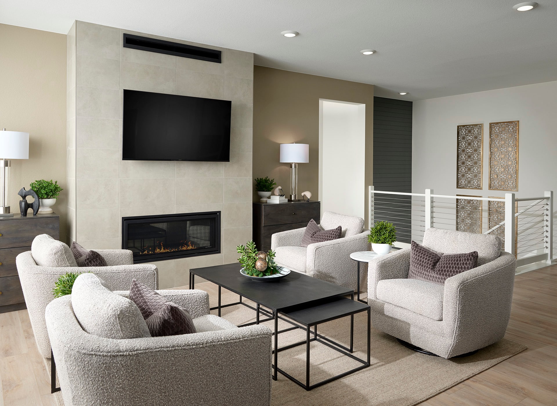 A modern and stylish living room with a fireplace, a large TV, and comfortable seating arrangements, including white sofas and armchairs, complemented by decorative elements such as plants and artwork.