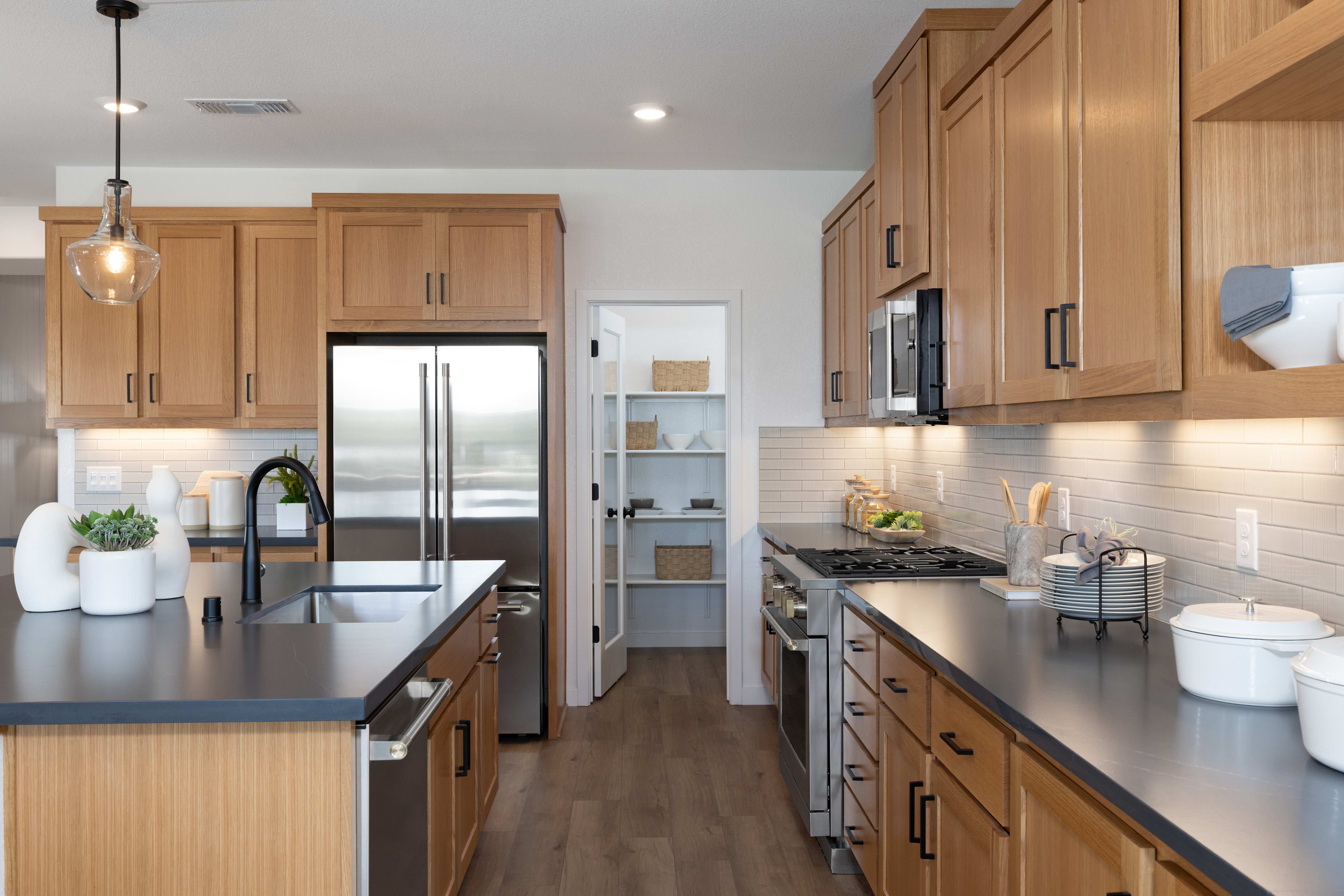 A modern and well-equipped kitchen with light wood cabinets, stainless steel appliances, and a sleek countertop, set against a neutral-toned backdrop.