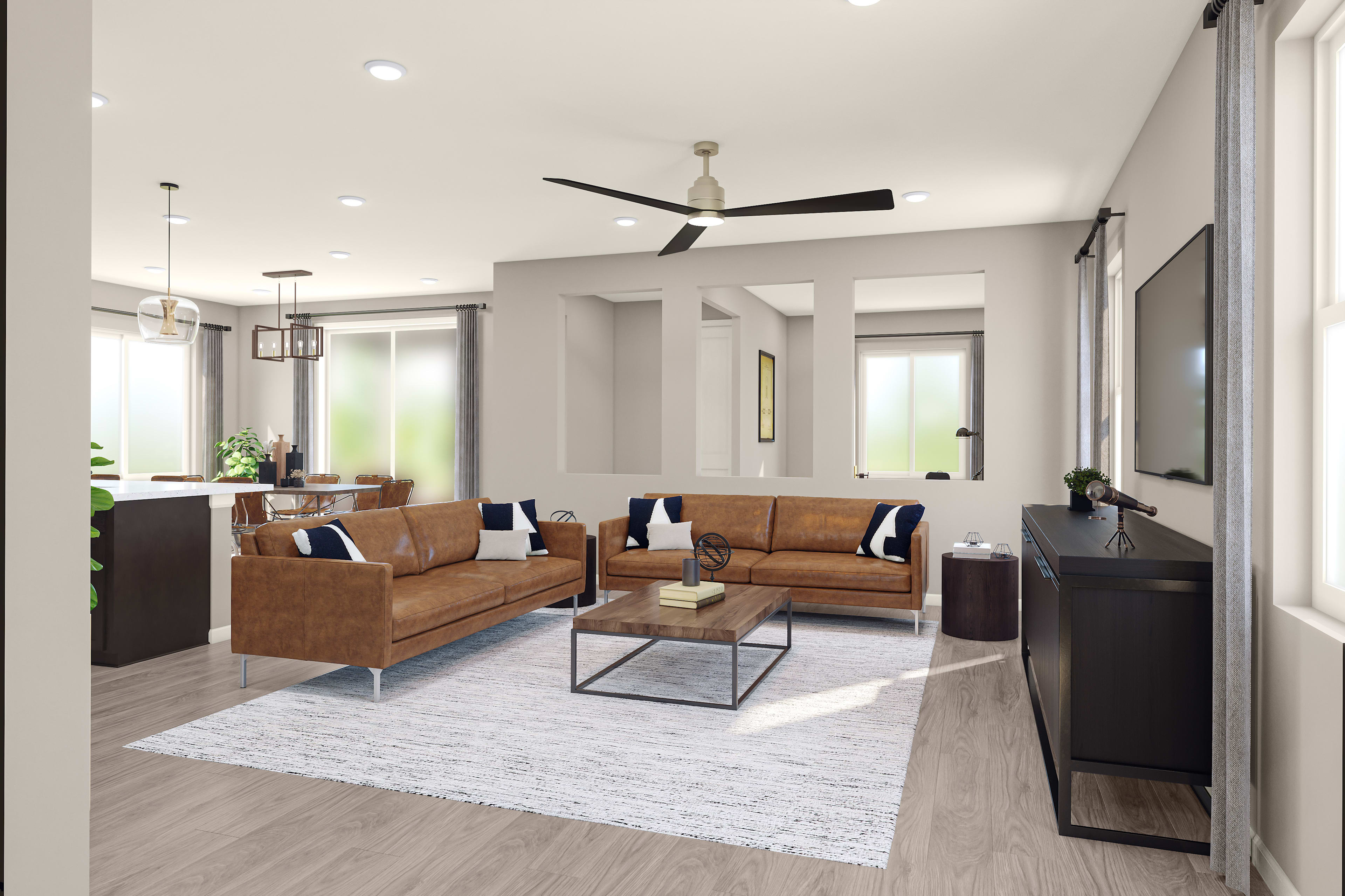 A modern and spacious living room with comfortable leather sofas, a coffee table, and a TV stand, all set against a backdrop of large windows and a ceiling fan.