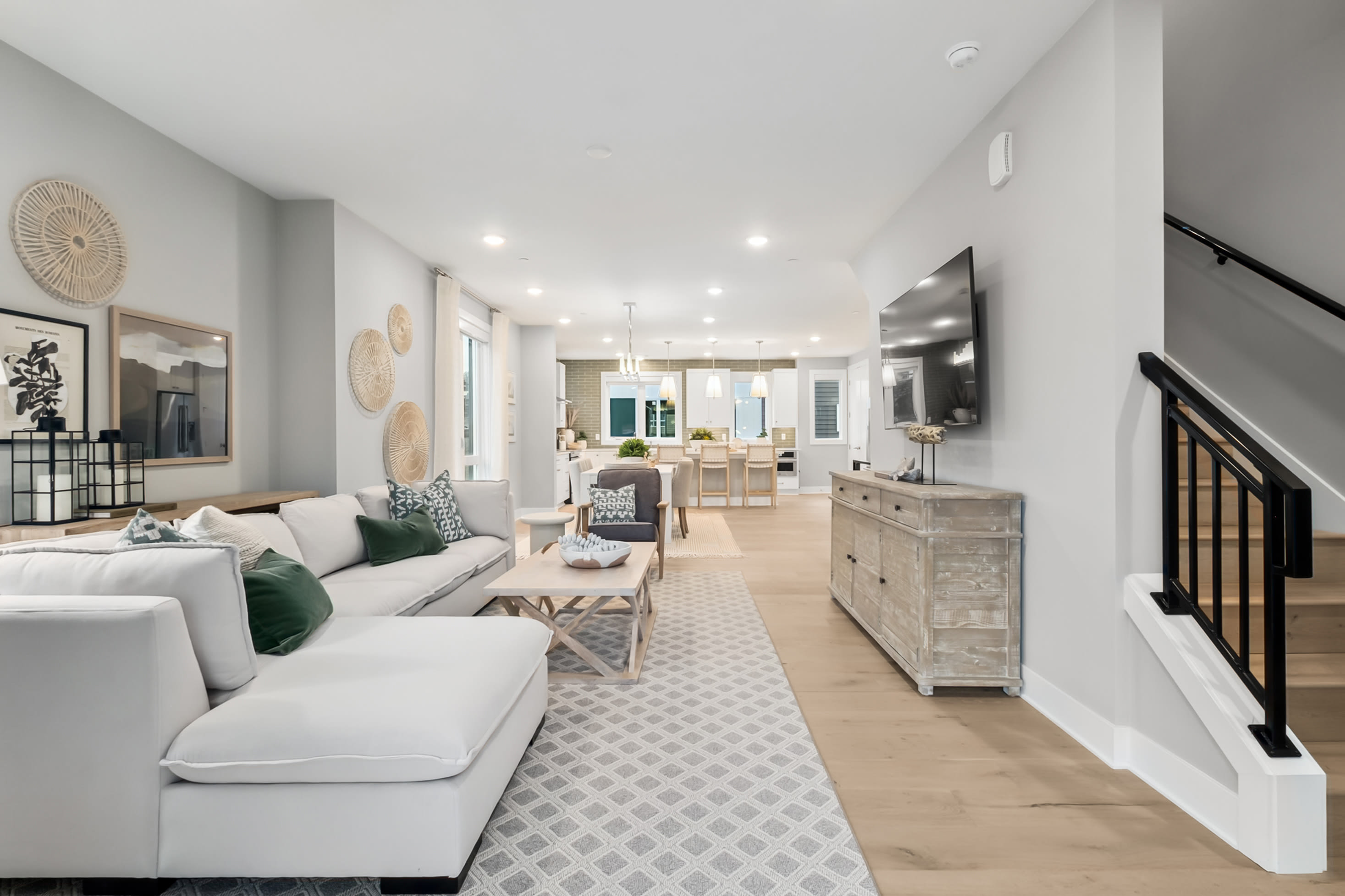 A spacious and well-designed living room with a comfortable white sofa, decorative accents, and an open-concept kitchen visible in the background, creating a harmonious and inviting atmosphere.
