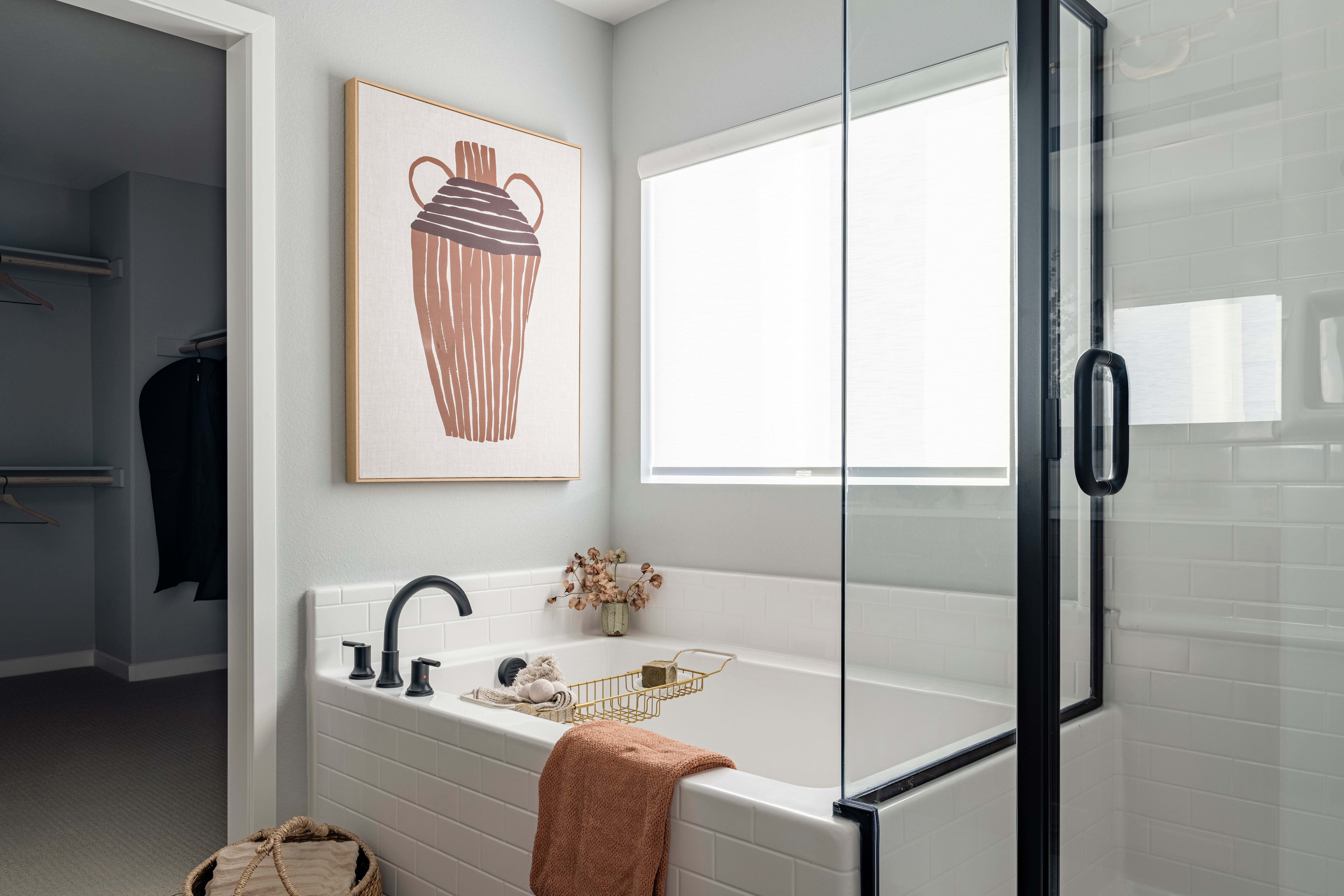 A modern bathroom with a glass shower enclosure, a tiled vanity, and a framed artwork depicting a cupcake on the wall.