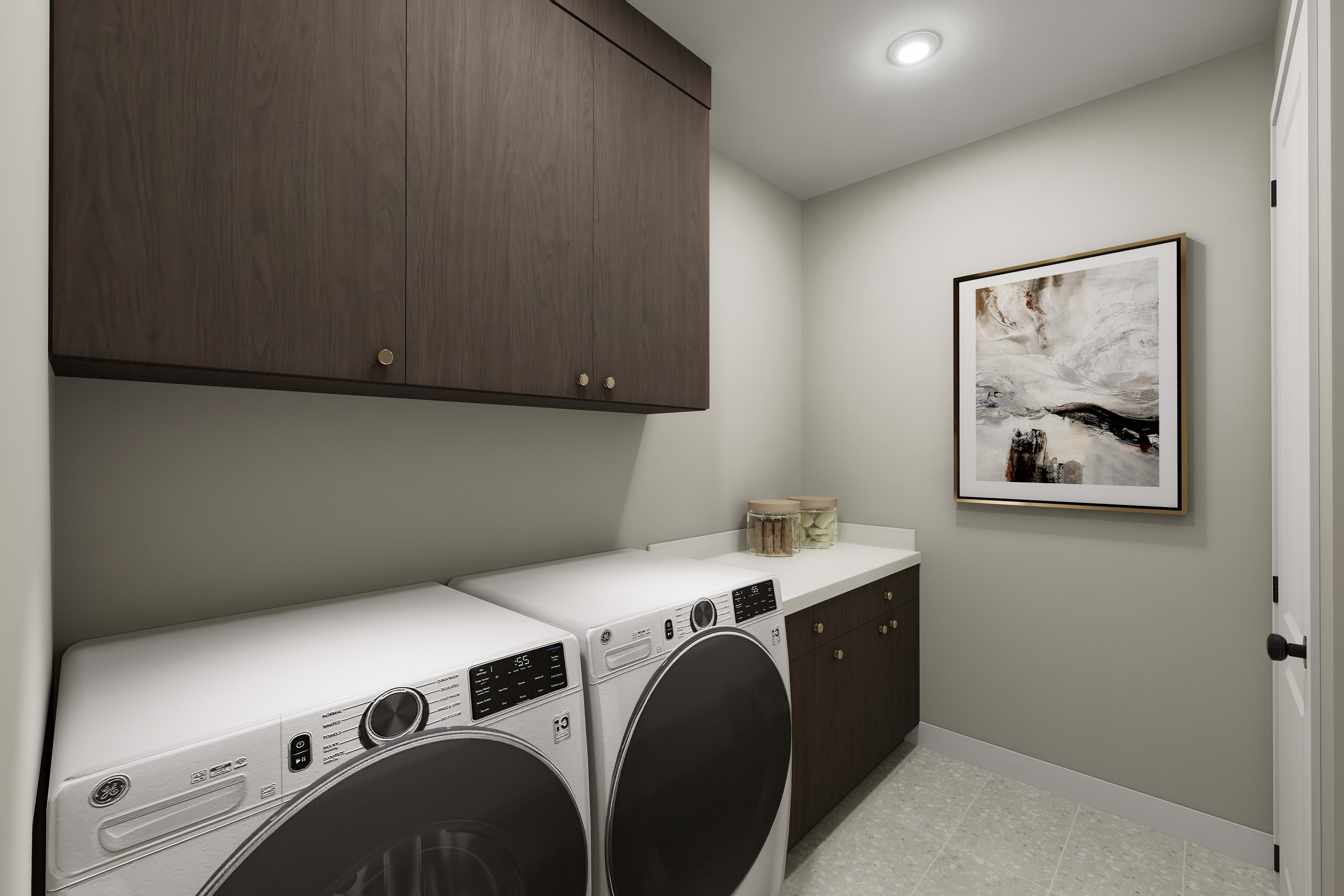 A modern and minimalist laundry room with a white washer and dryer set against a dark wood cabinet, complemented by a framed artwork on the wall.