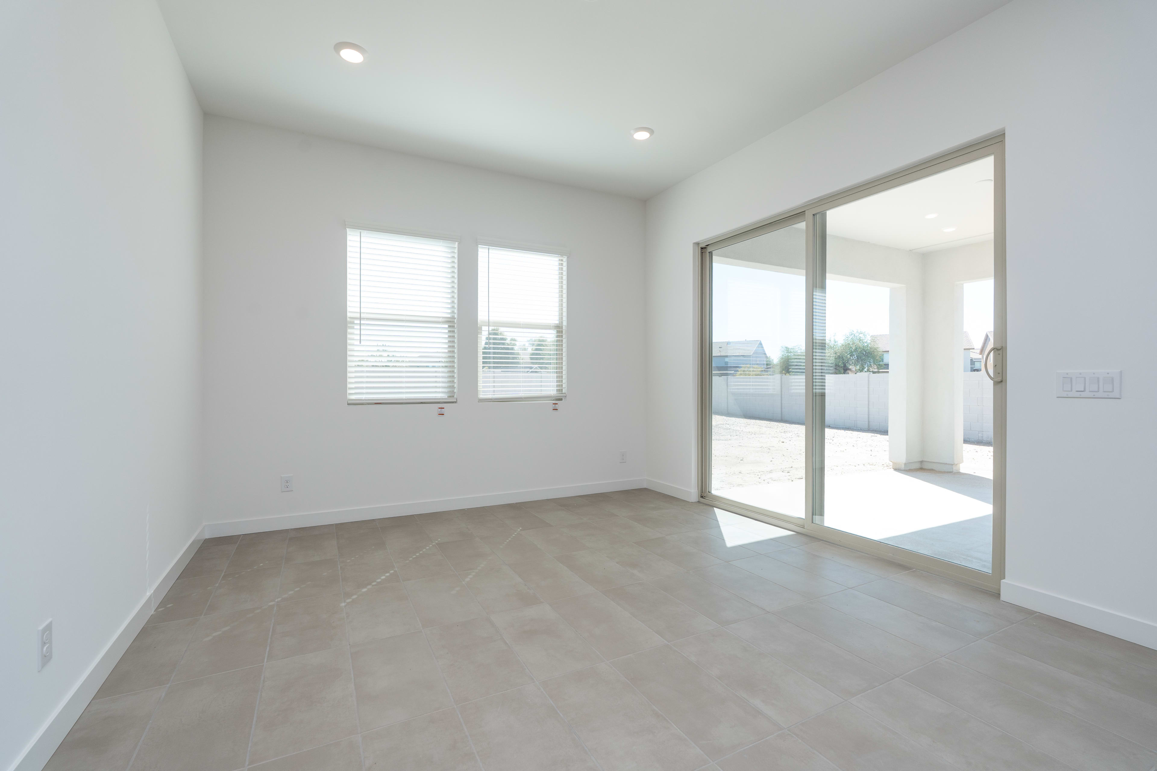 A bright, minimalist room with large windows, a sliding glass door, and a smooth concrete floor.