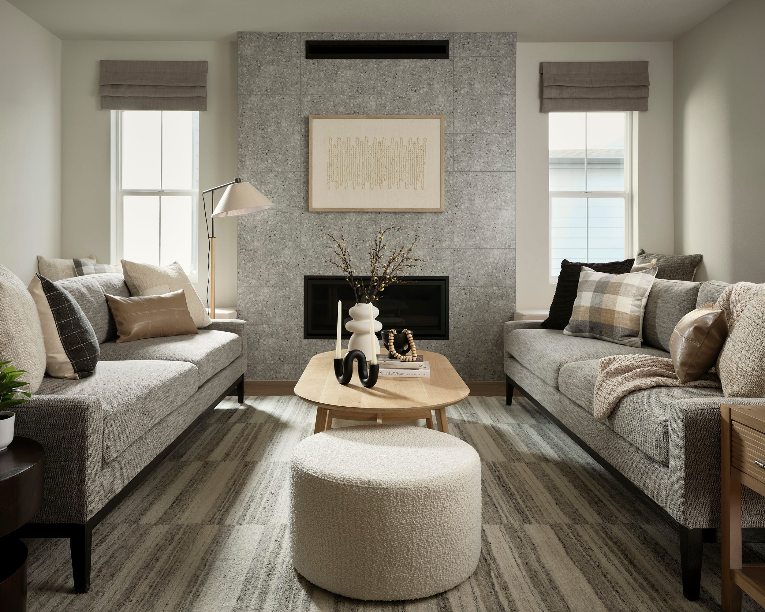A cozy and inviting living room with plush gray sofas, a wooden coffee table, and a fireplace with a decorative frame on the wall, creating a warm and comfortable atmosphere.