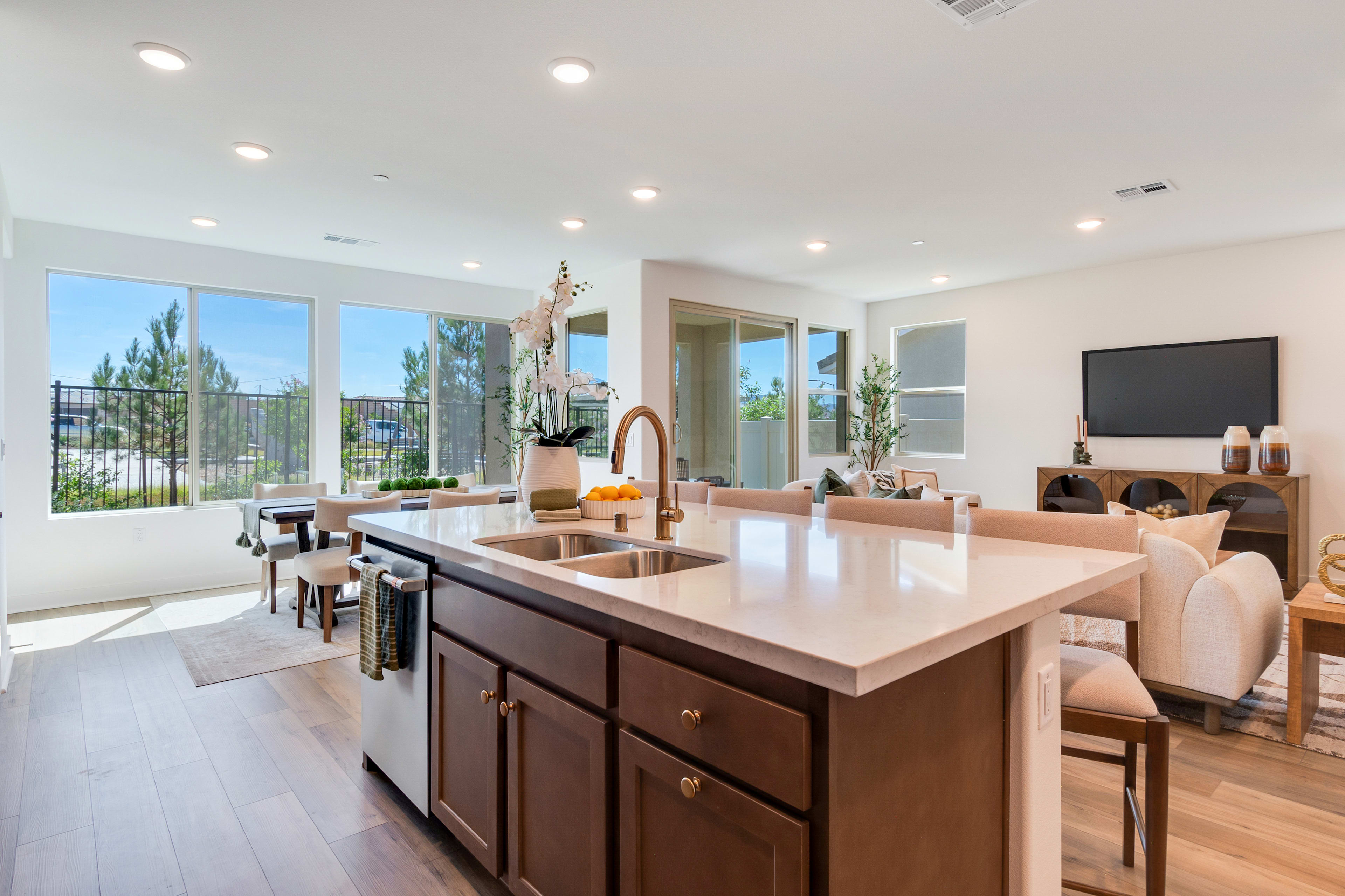 A modern and spacious kitchen with a large island, wooden cabinets, and large windows overlooking a scenic outdoor area.