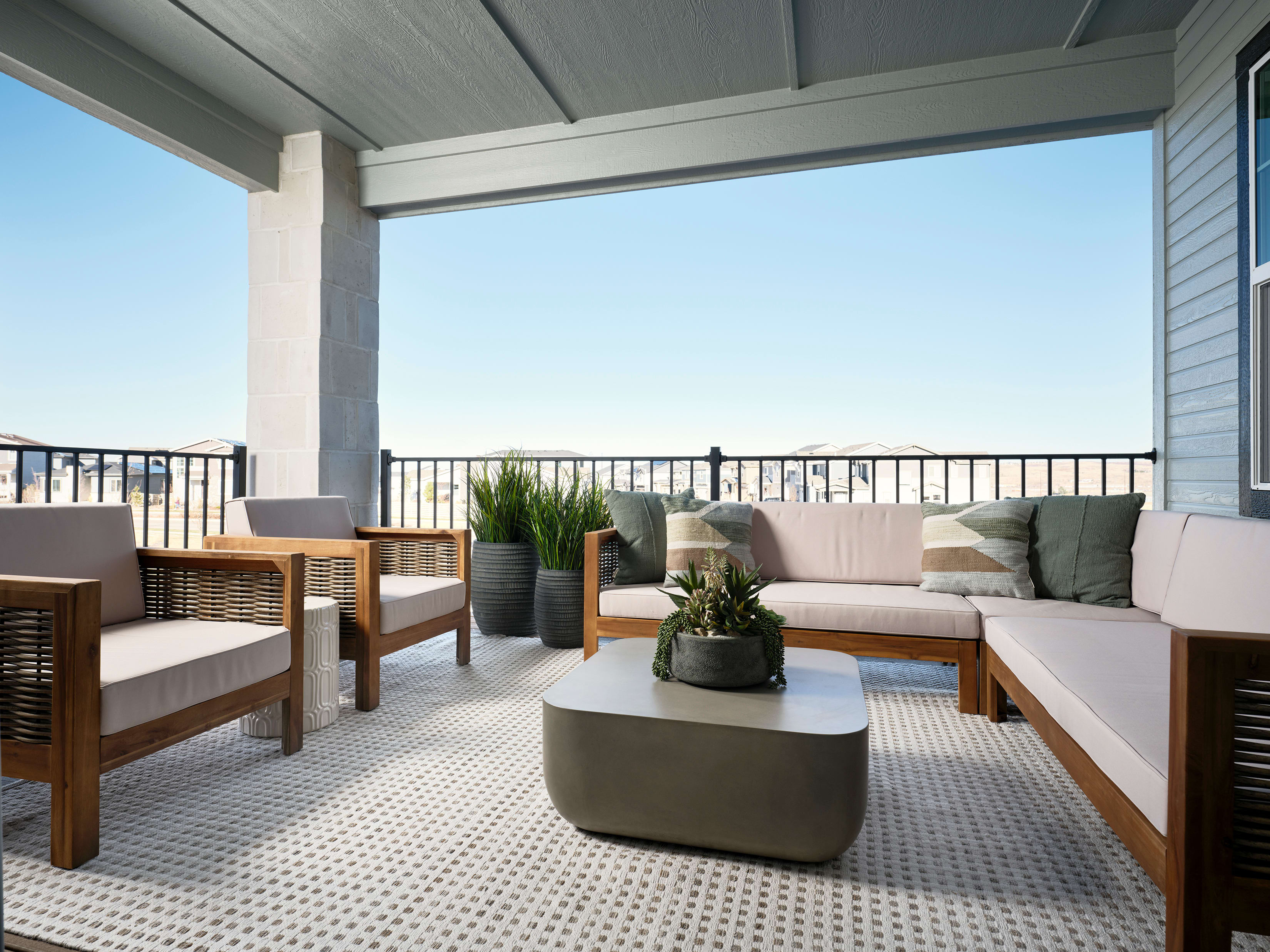 A cozy outdoor patio with comfortable seating, potted plants, and a view of the sky and surrounding landscape.