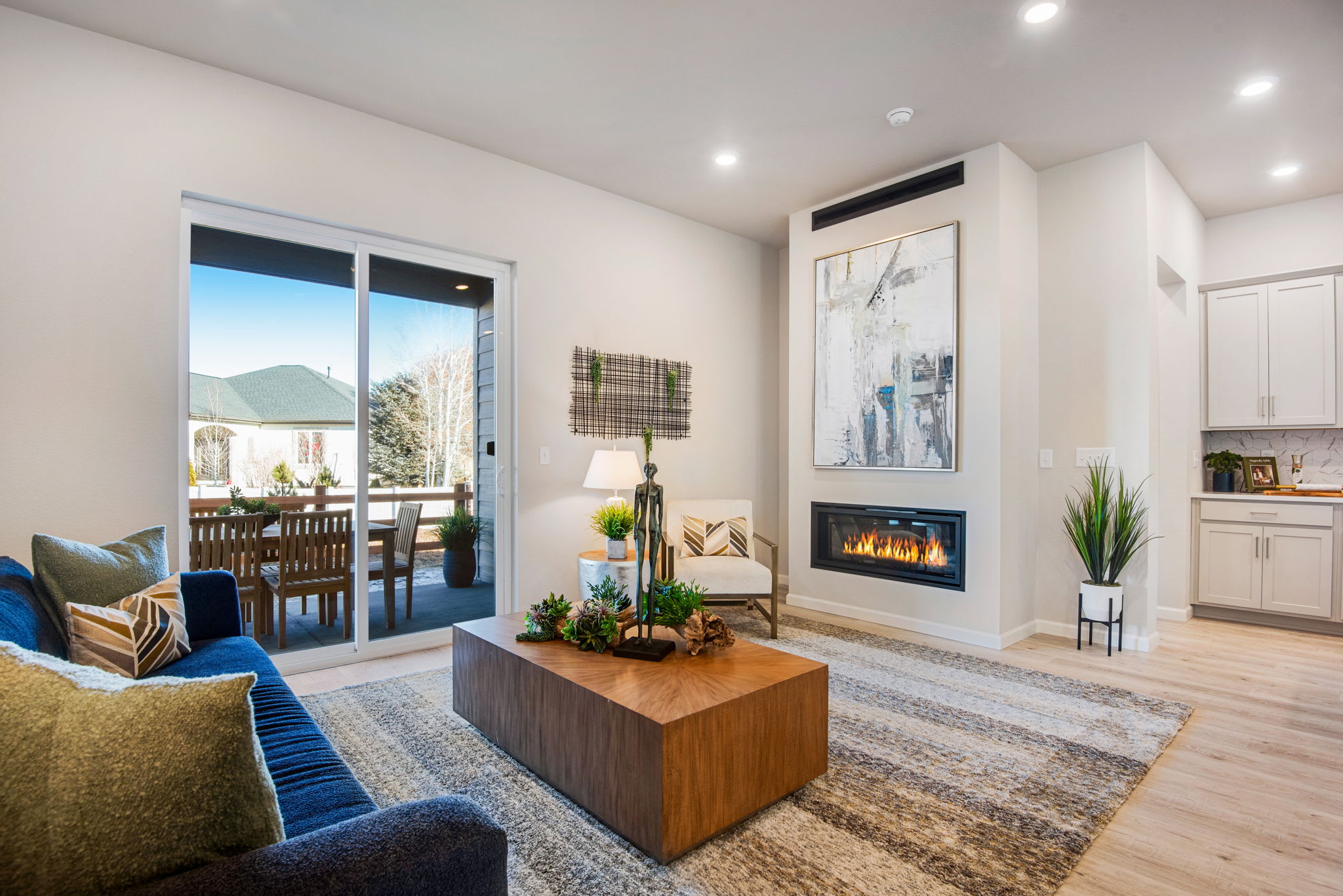 A cozy and modern living room with a fireplace, large windows overlooking a scenic outdoor view, and a mix of comfortable furniture and decor elements.