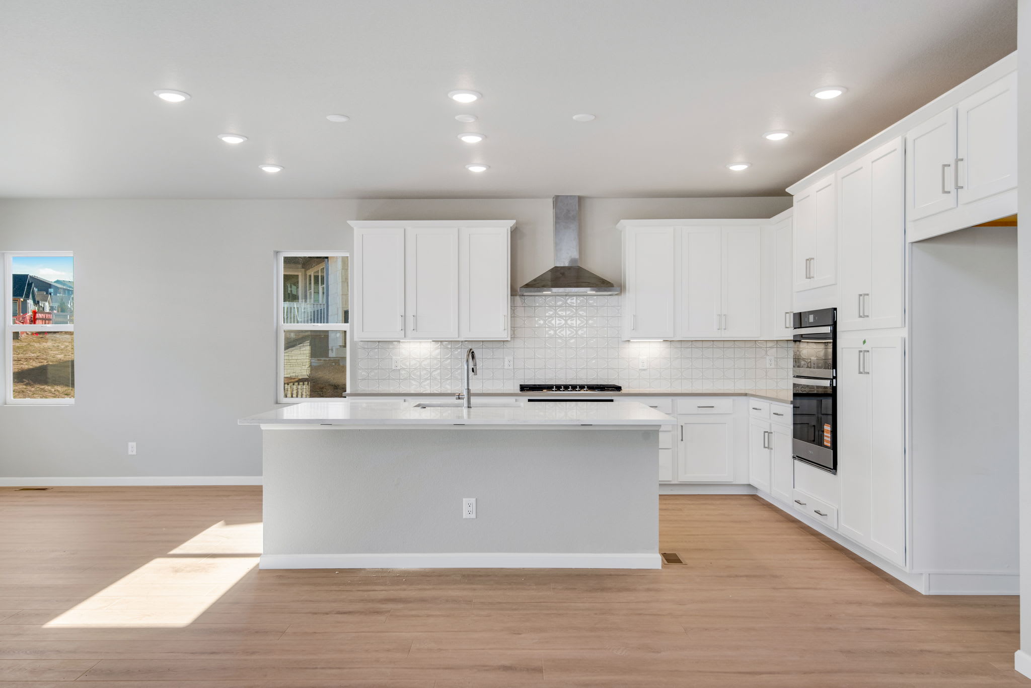 A modern, bright, and spacious kitchen with white cabinets, a central island, and hardwood floors.