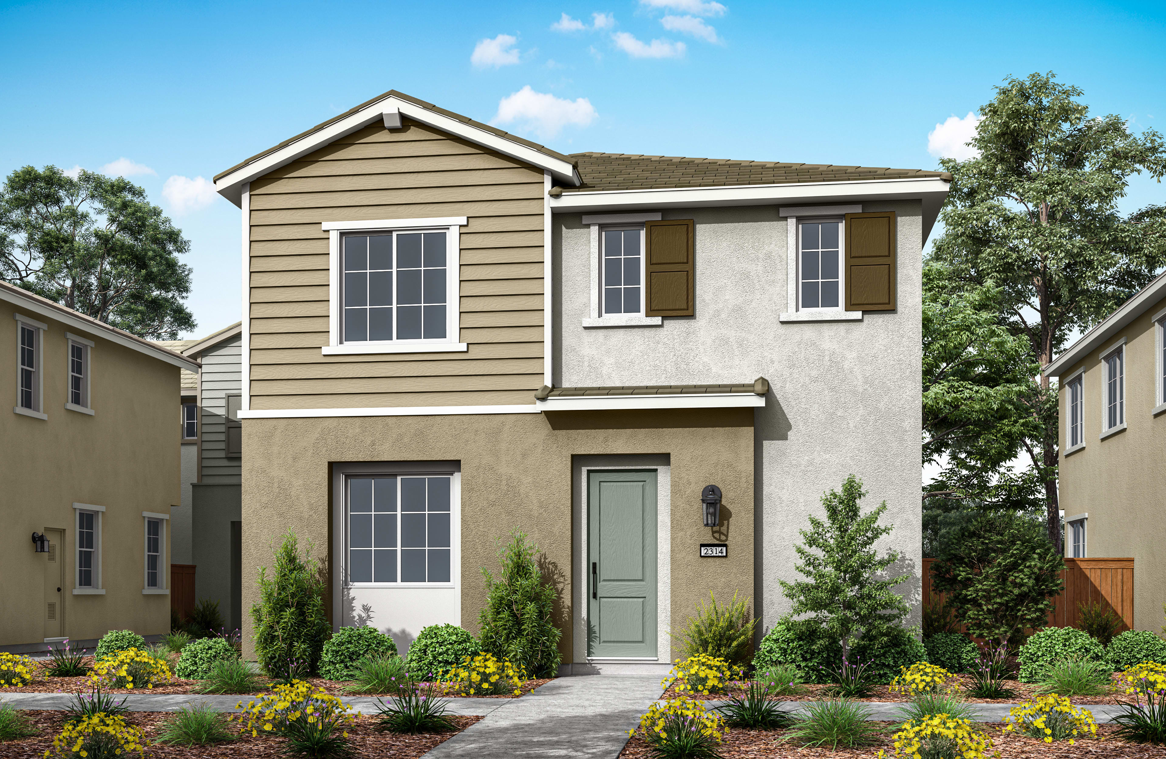 A two-story residential house with a tan exterior, a green front door, and a well-landscaped yard with trees and flowers in the foreground.