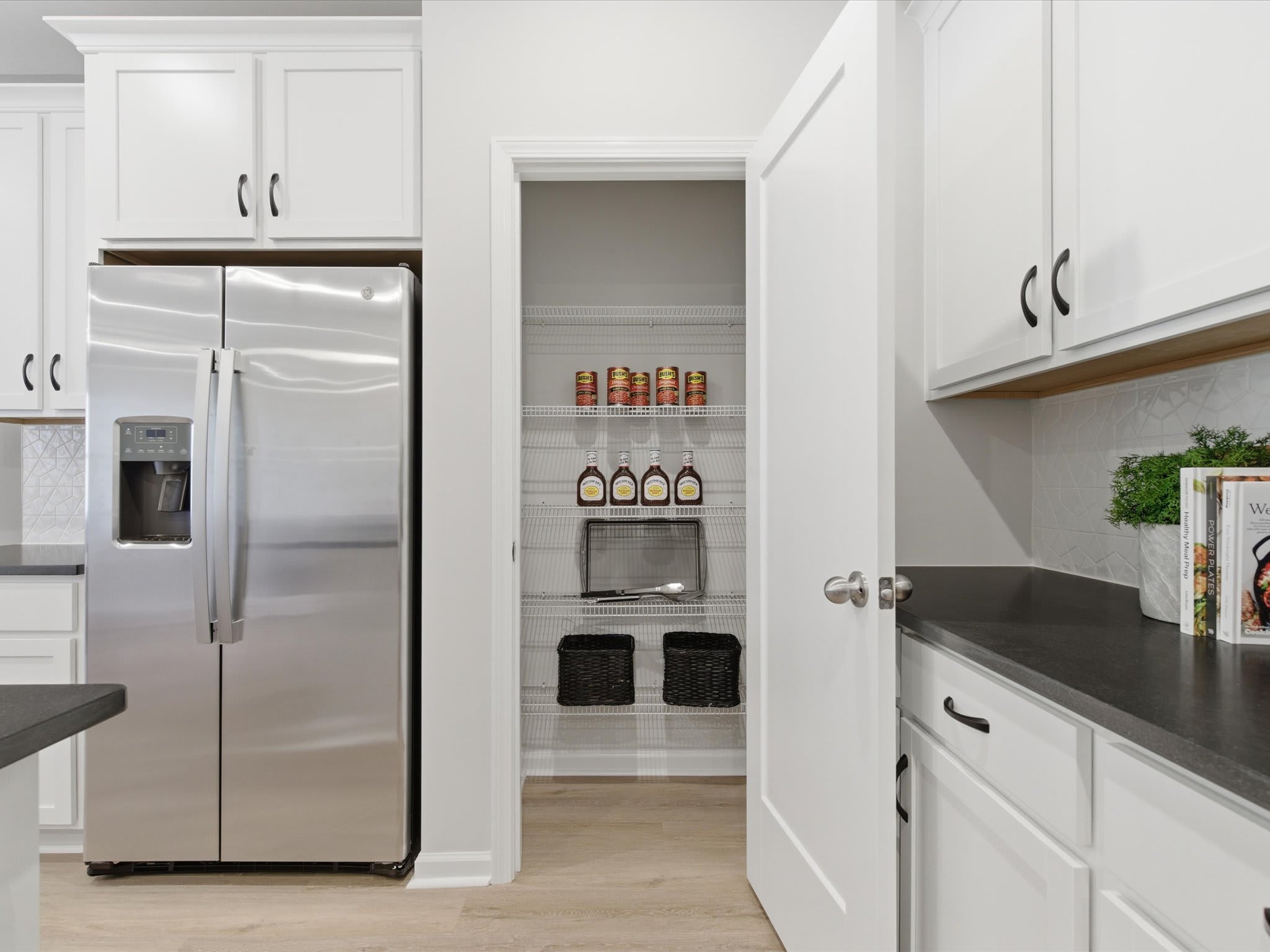 A modern, well-equipped kitchen with white cabinets, stainless steel appliances, and a pantry visible in the background.