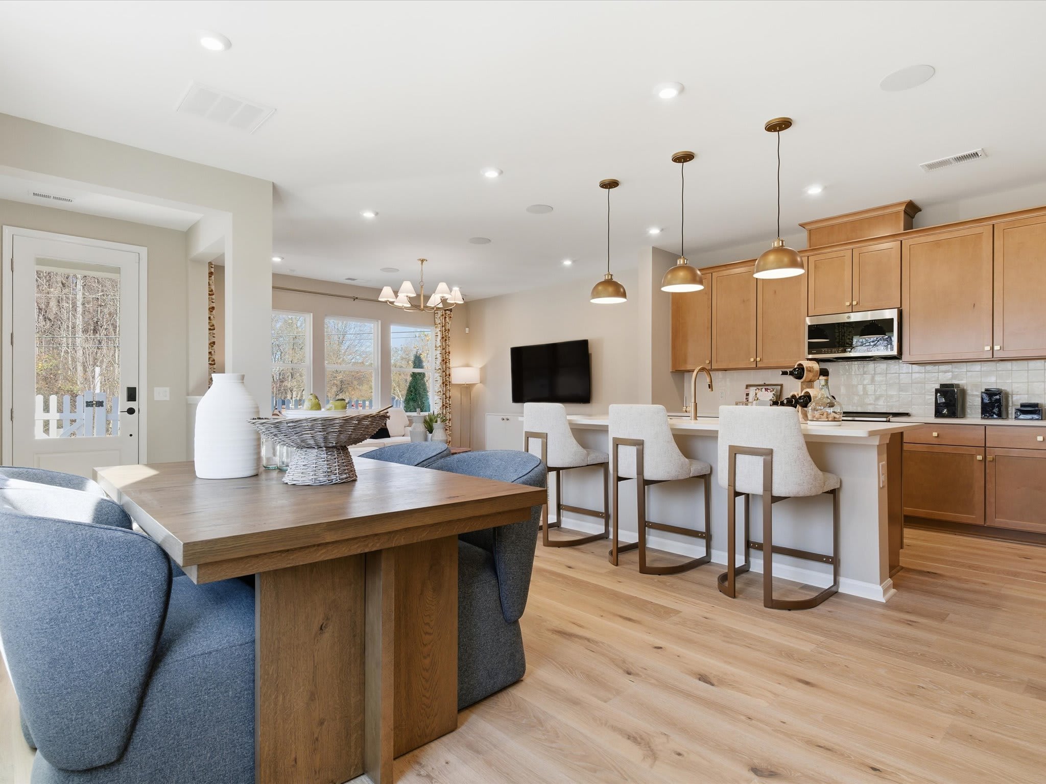 A modern and spacious open-concept kitchen and living room with wooden furniture, pendant lights, and a large dining table.
