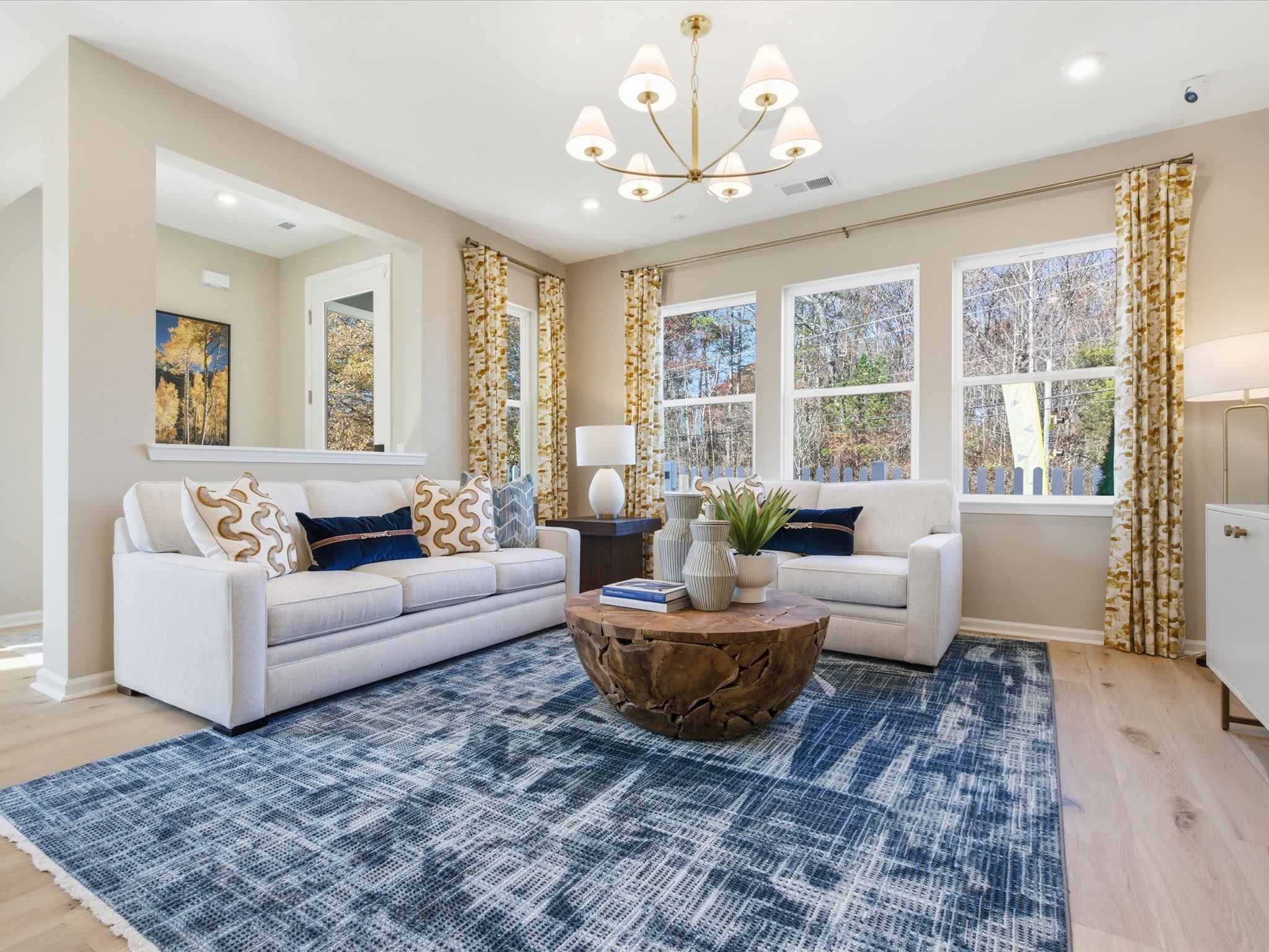 A cozy and well-decorated living room with plush sofas, a patterned rug, and a large window overlooking a scenic outdoor view.