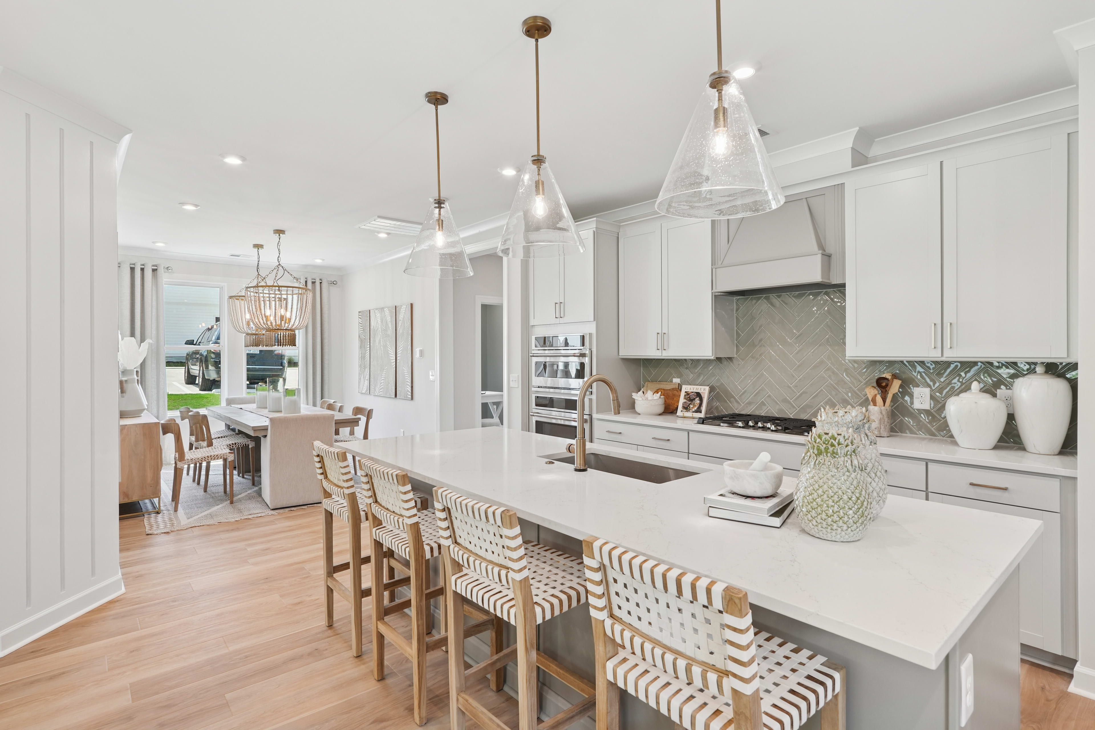A modern, bright, and spacious kitchen with white cabinets, a large island with bar stools, and pendant lighting fixtures creating a warm and inviting atmosphere.
