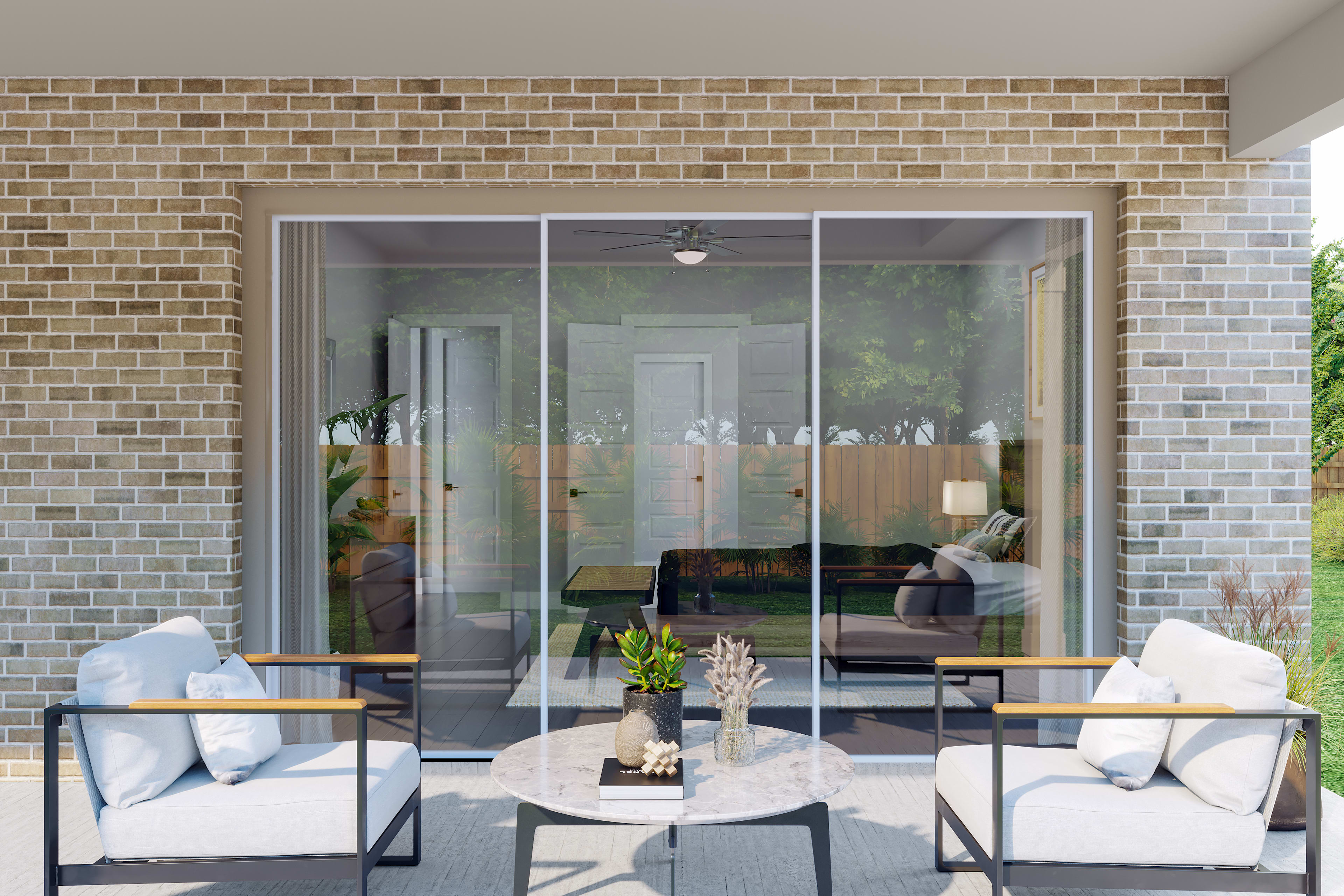 A cozy outdoor seating area with comfortable chairs and a coffee table, surrounded by a brick wall and glass doors leading to an interior space.