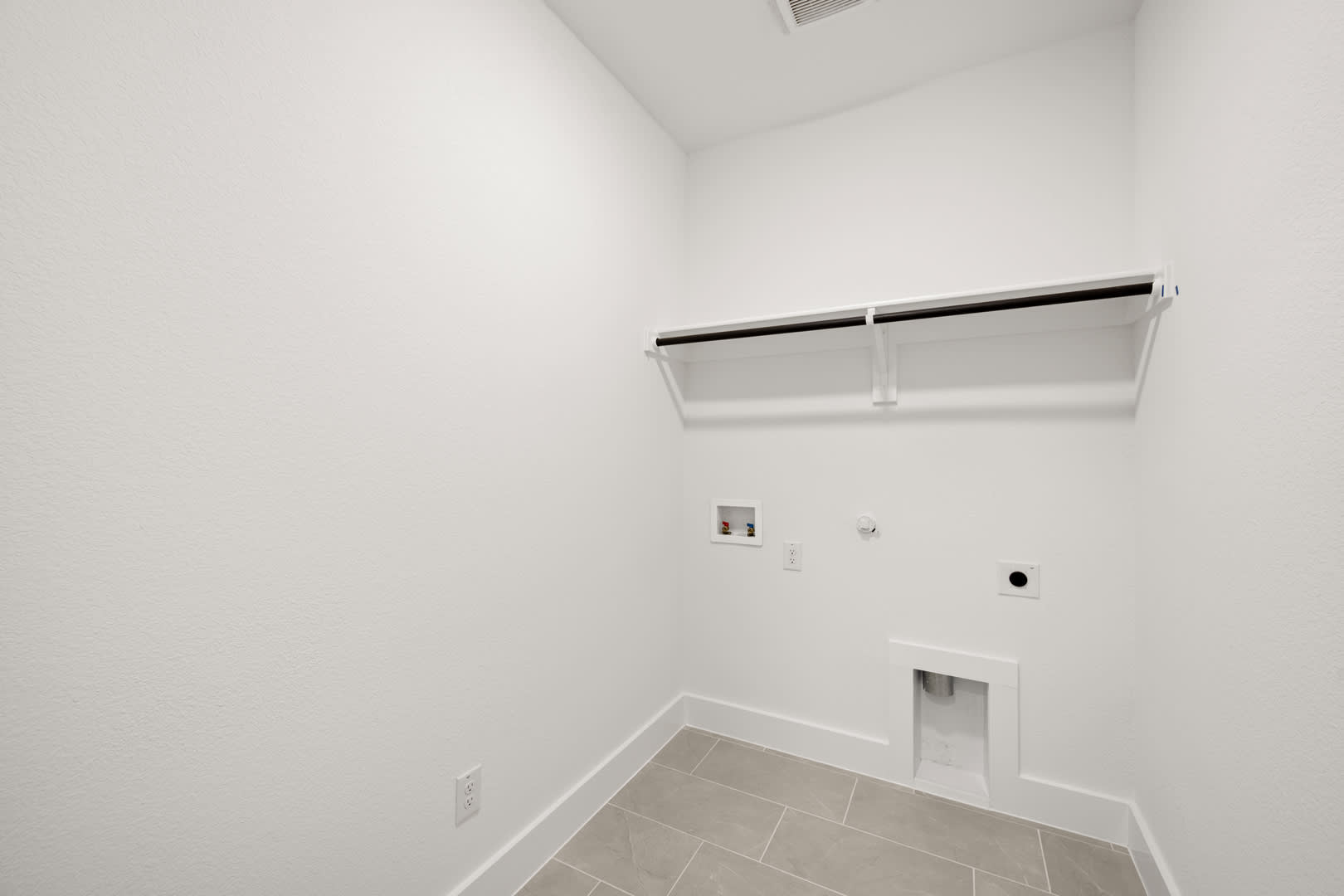 A minimalist, white-walled room with a tiled floor and a recessed lighting fixture on the ceiling.