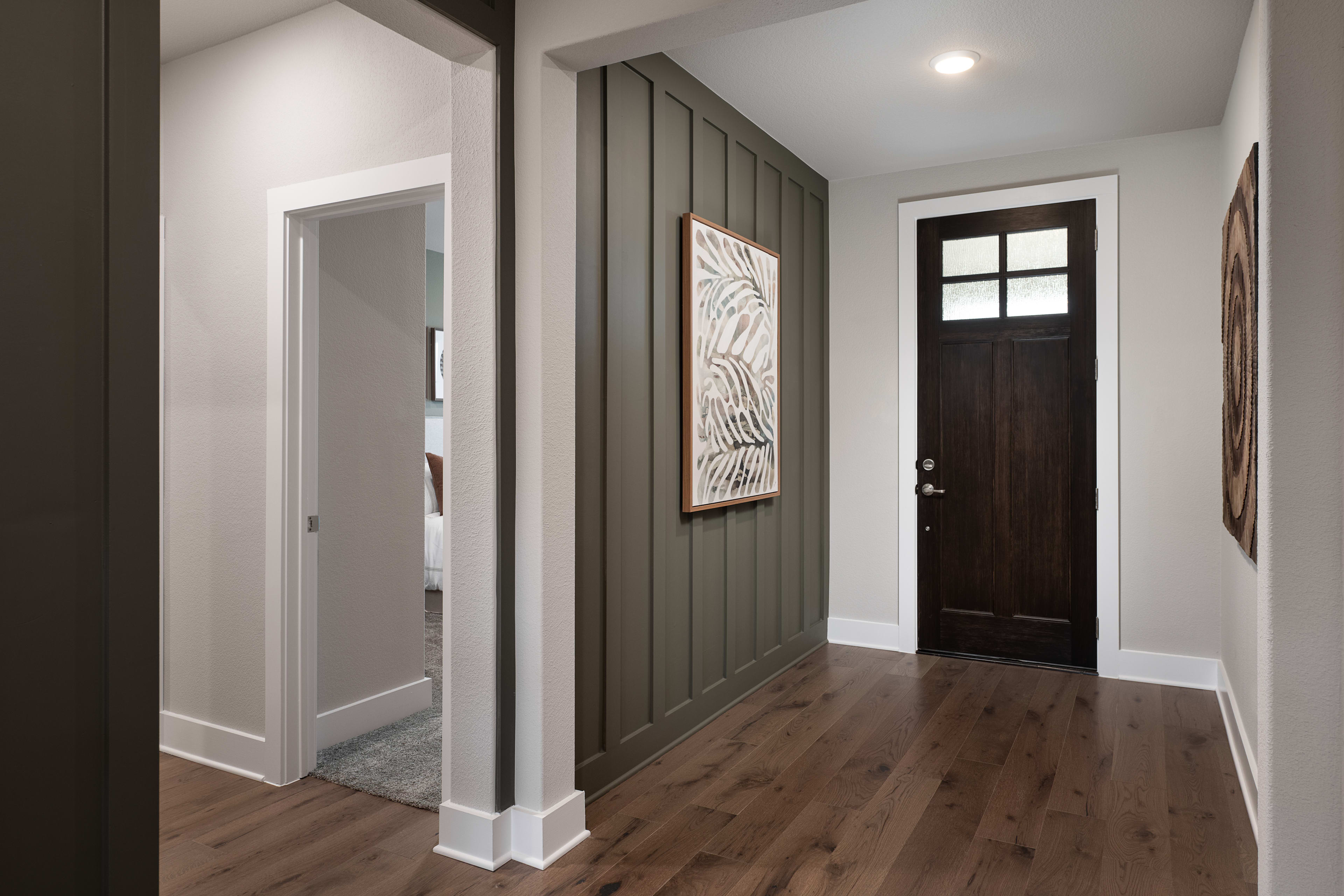 A modern and minimalist entryway with a dark wooden door, a gray accent wall, and a framed artwork hanging on the wall.
