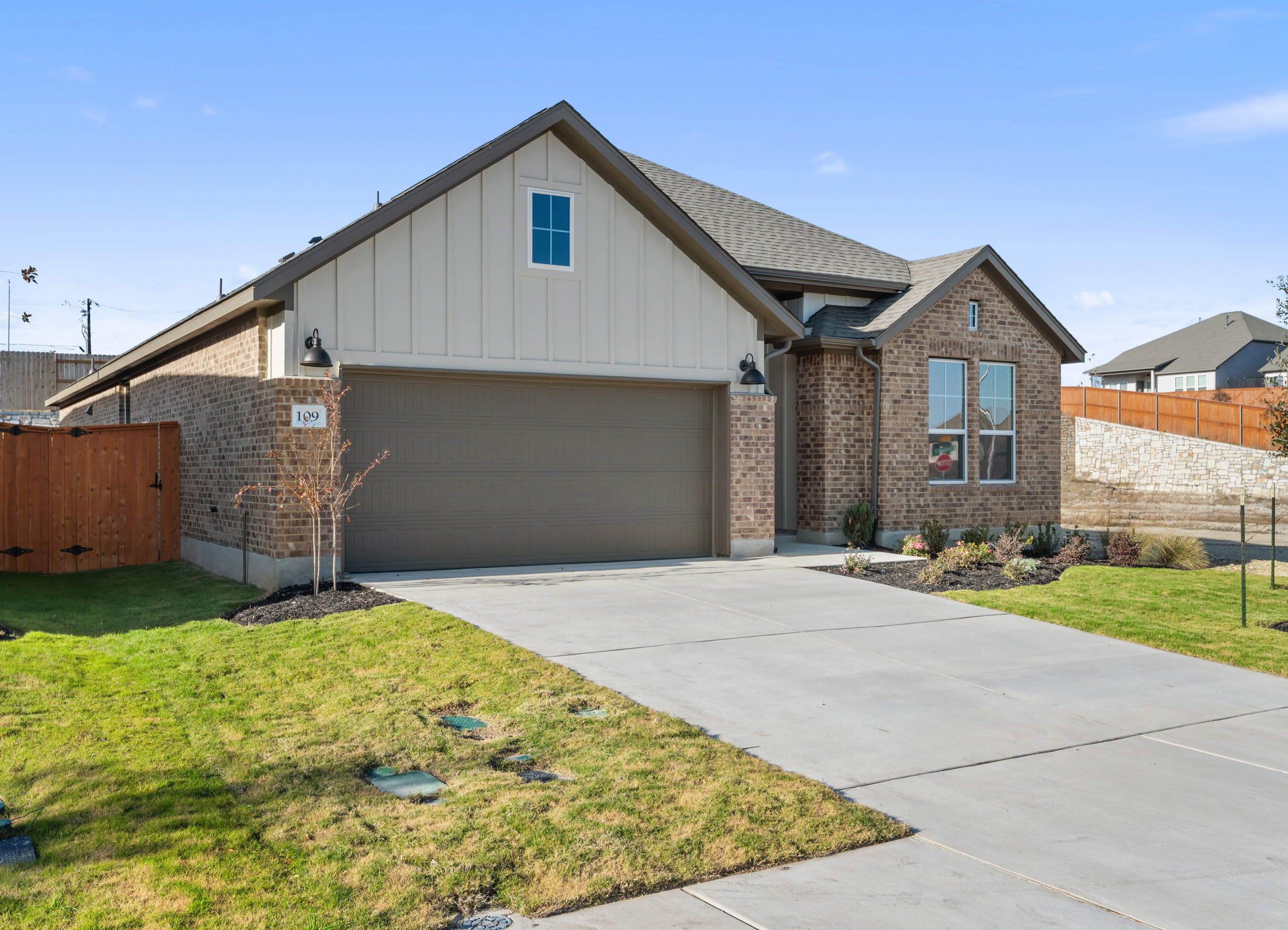 A modern two-story house with a brick and siding exterior, a garage, and a well-maintained lawn in the foreground.