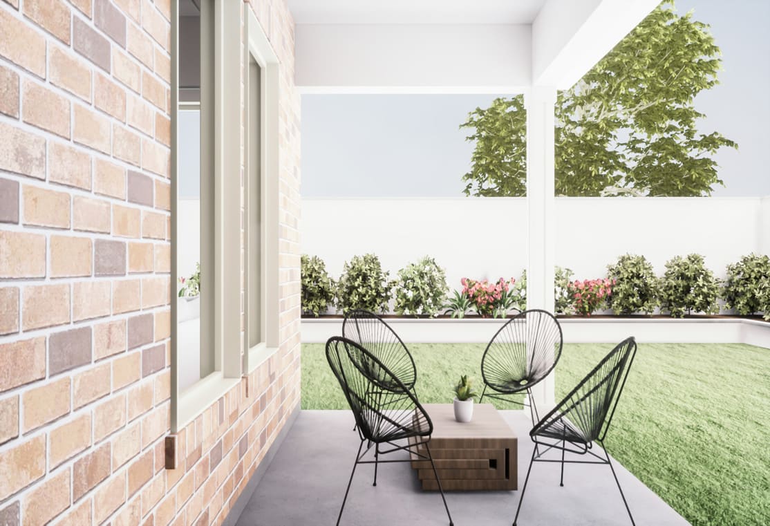 A cozy outdoor patio with a wooden table and black wire chairs, surrounded by lush greenery and a brick wall, creating a serene and inviting atmosphere.