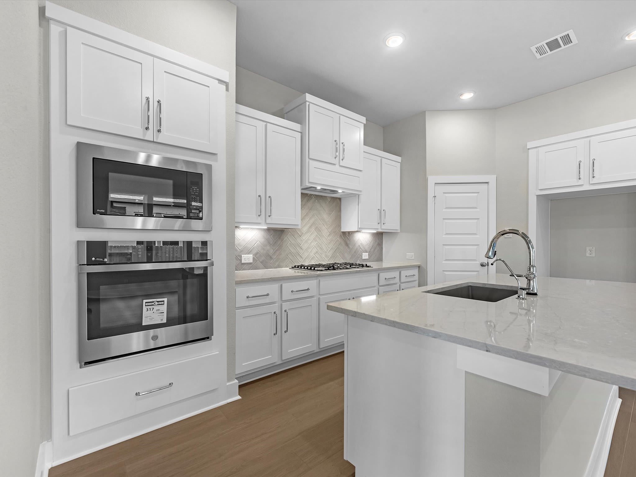 A modern, well-equipped kitchen with white cabinets, stainless steel appliances, and a sleek, minimalist design.