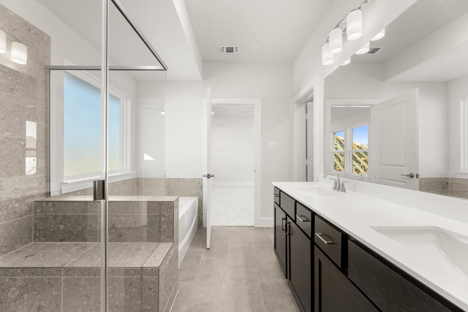 A modern, spacious bathroom with a large vanity, tiled walls, and a glass-enclosed shower area.