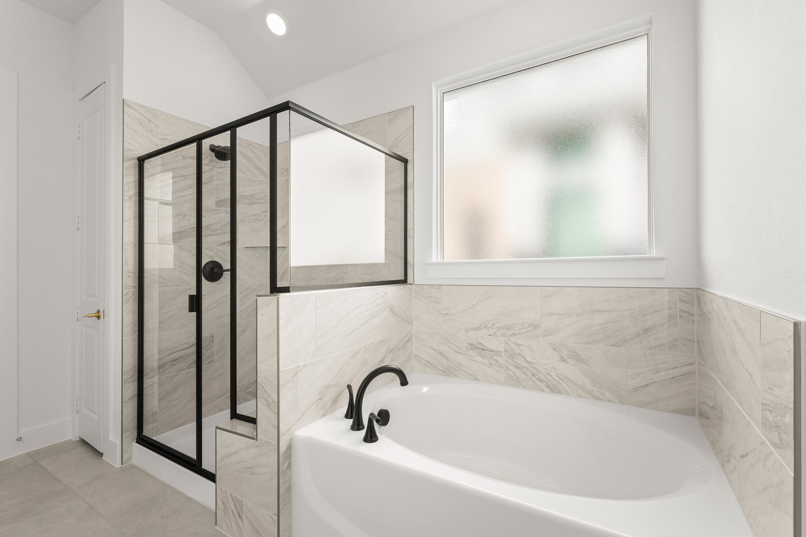 A modern, minimalist bathroom with a freestanding bathtub, a glass-enclosed shower, and a large window providing natural light.
