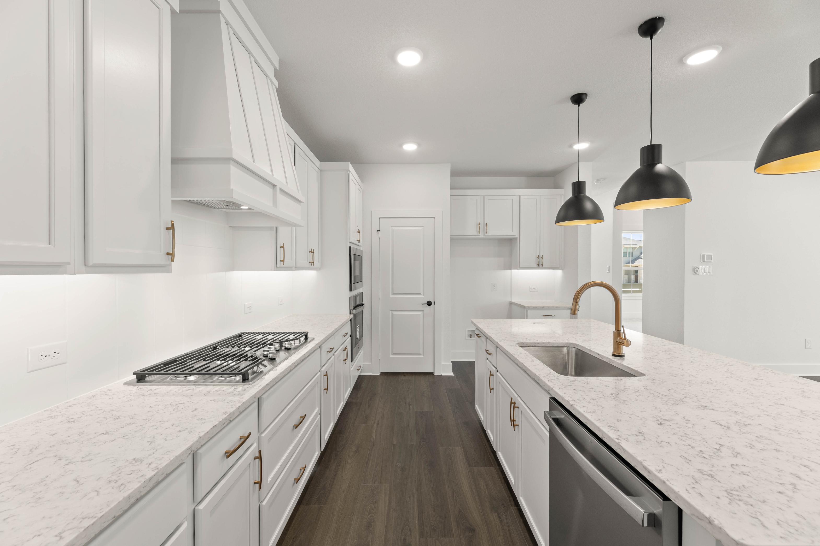 A modern, bright, and spacious kitchen with white cabinets, granite countertops, and pendant lighting fixtures, creating a sleek and stylish atmosphere.