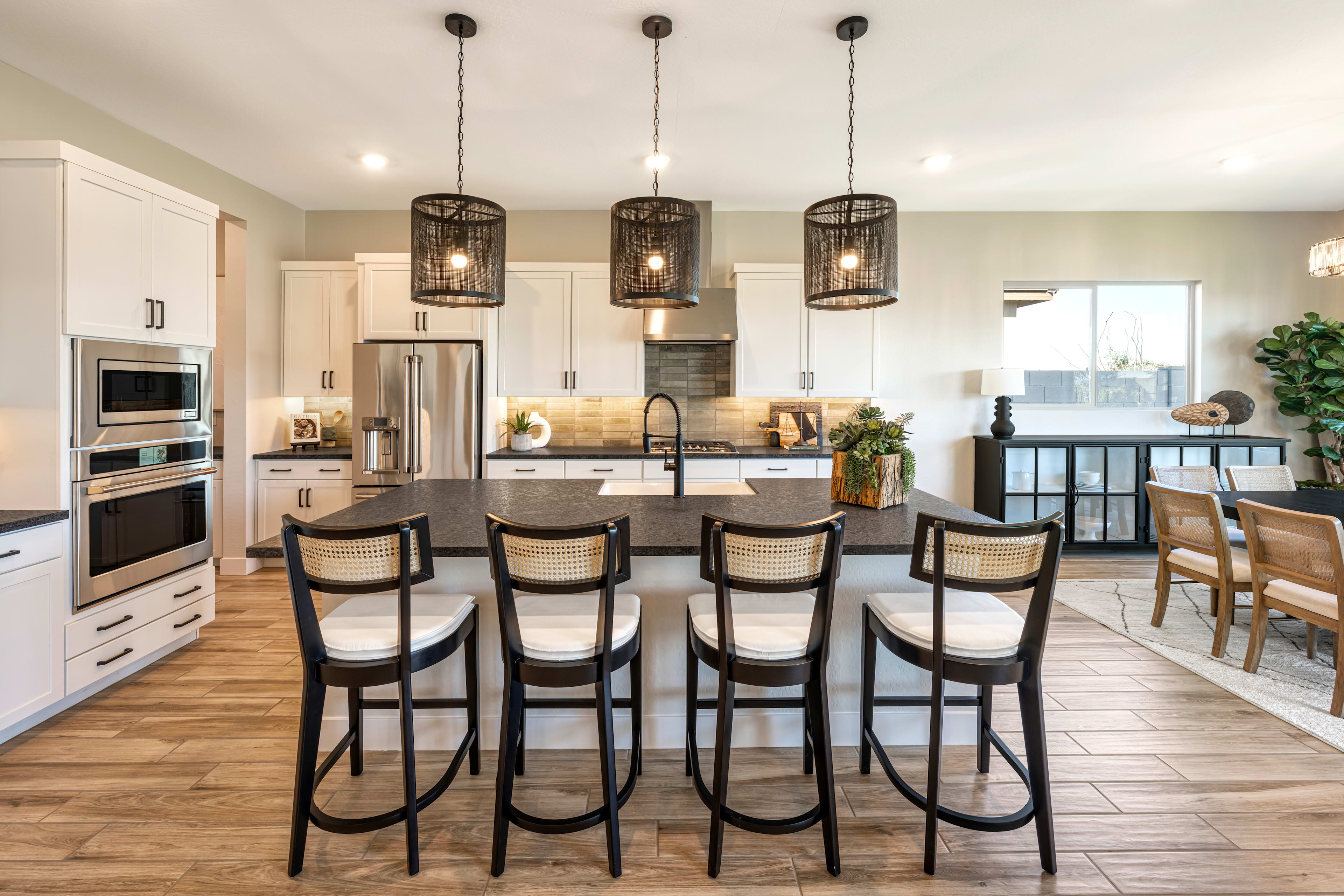 A modern and spacious kitchen with a large island, pendant lighting, and wooden floors, featuring a mix of contemporary and rustic design elements.