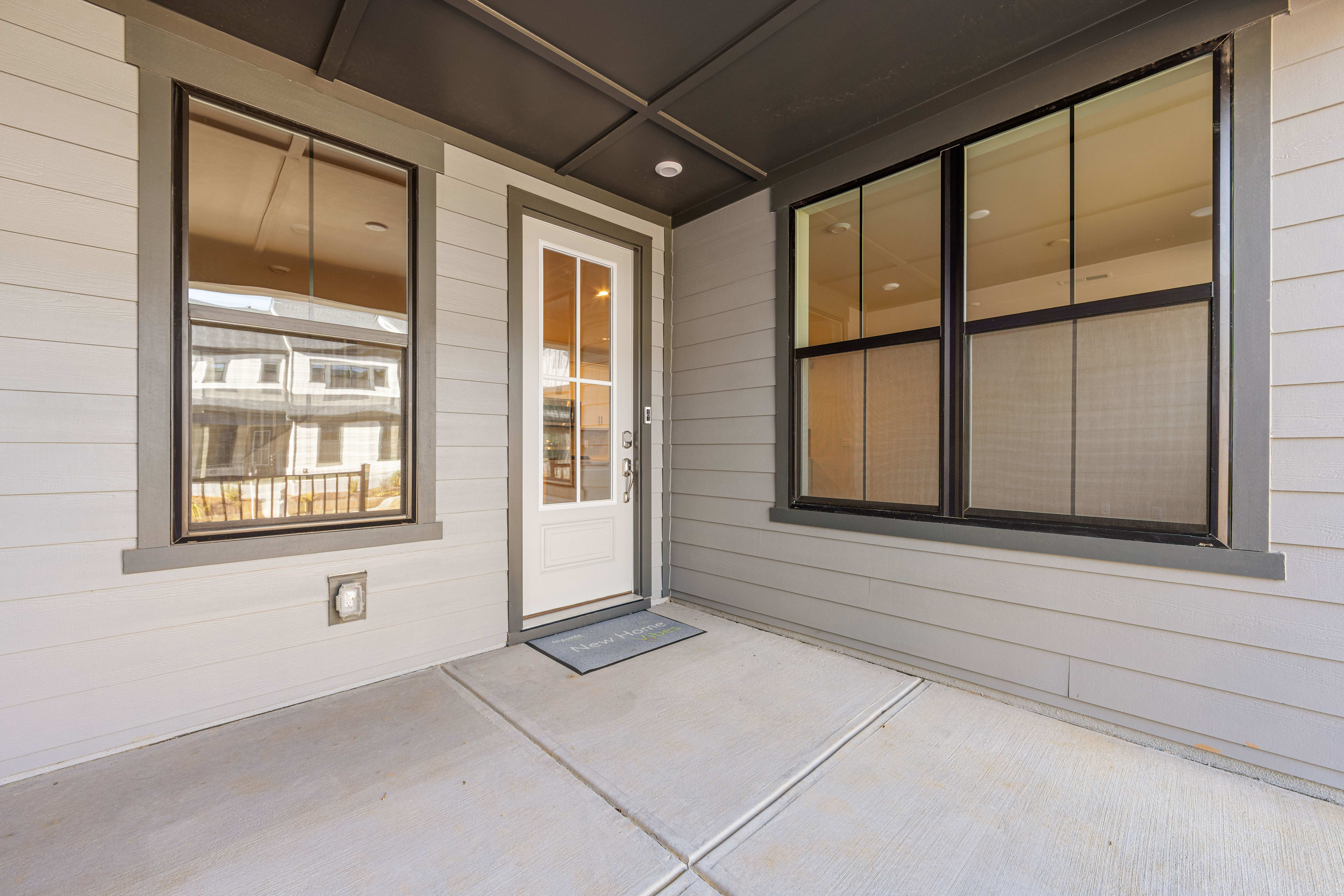 A modern, minimalist entryway with a white exterior, large windows, and a tiled floor leading into the interior of the building.