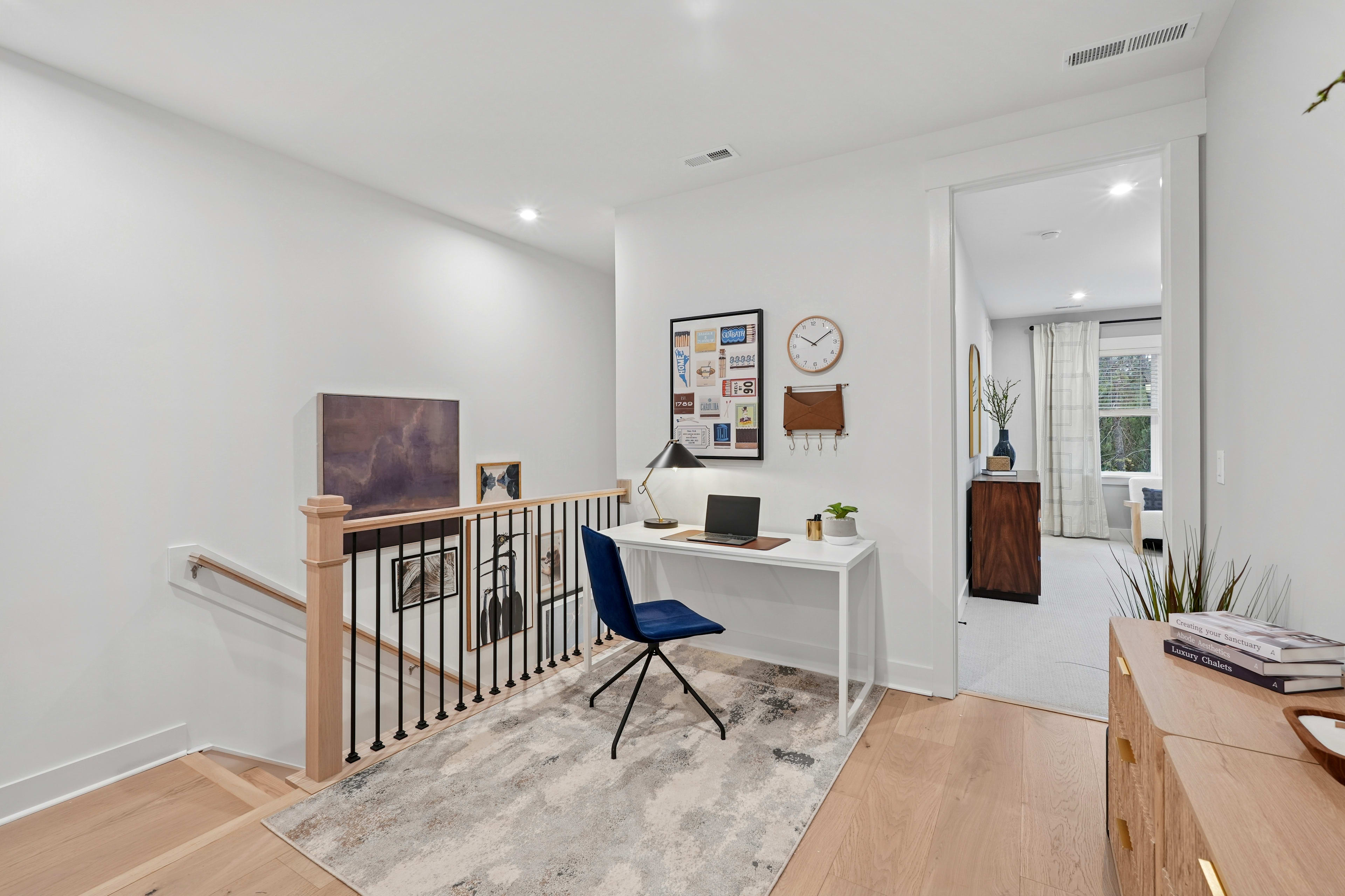 A modern, minimalist home office space with a white desk, blue chair, and various decorative elements on the walls.