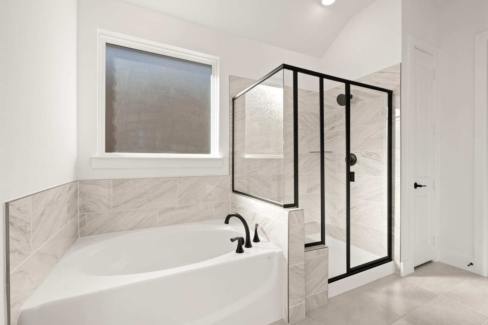 A modern, minimalist bathroom with a freestanding bathtub, a glass-enclosed shower, and a large window providing natural light.