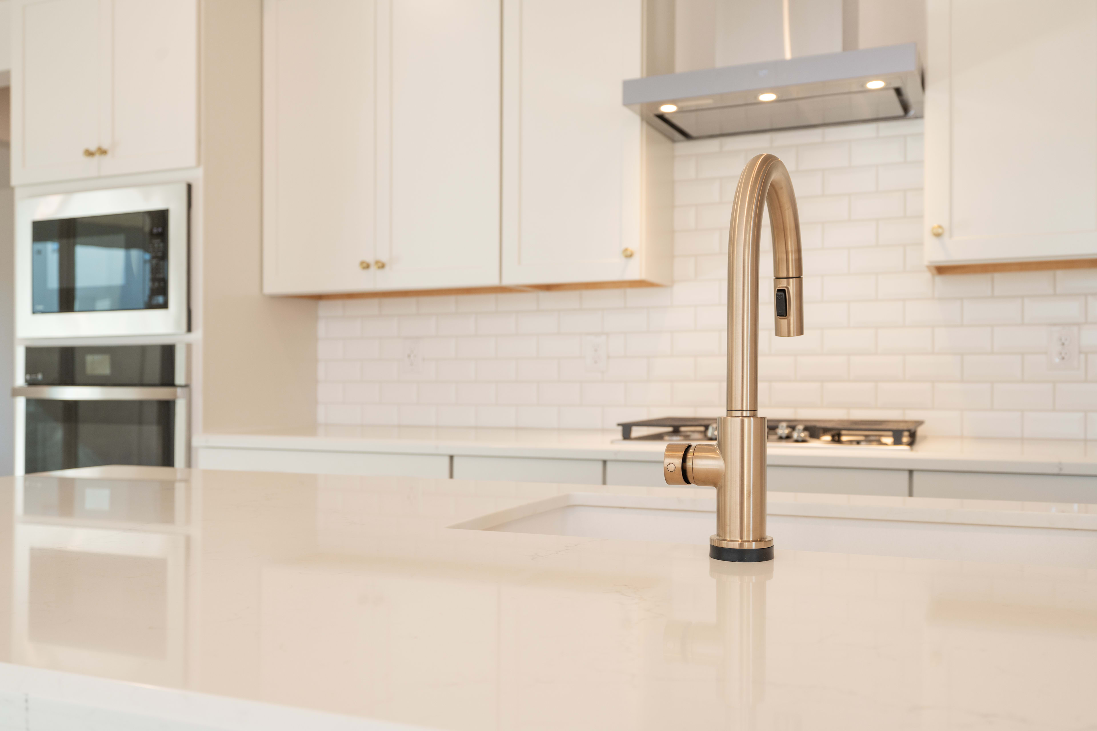 A modern kitchen with white cabinets, a stainless steel faucet, and a clean, minimalist design.