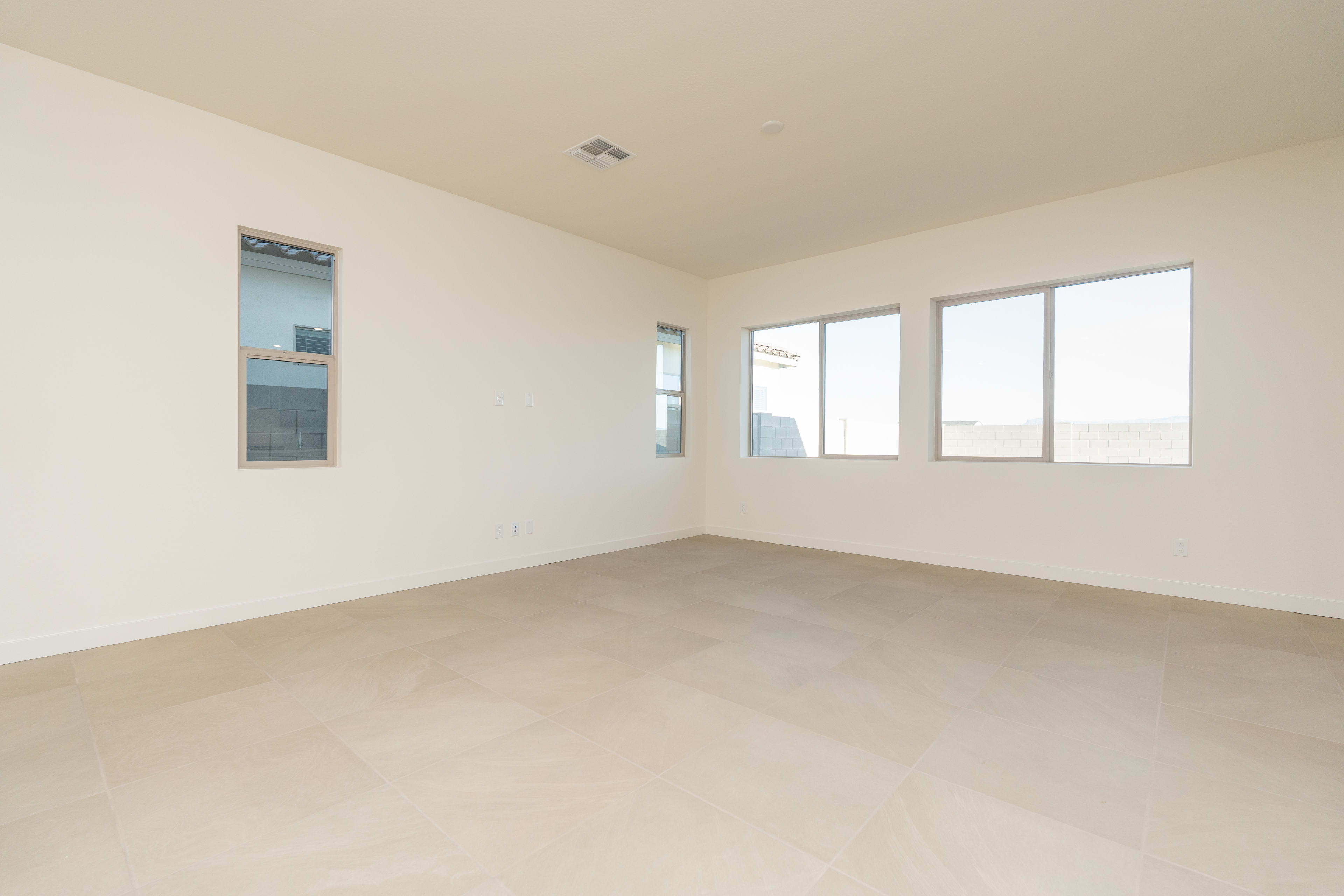 A spacious, minimalist room with large windows, a bare floor, and a recessed wall niche.