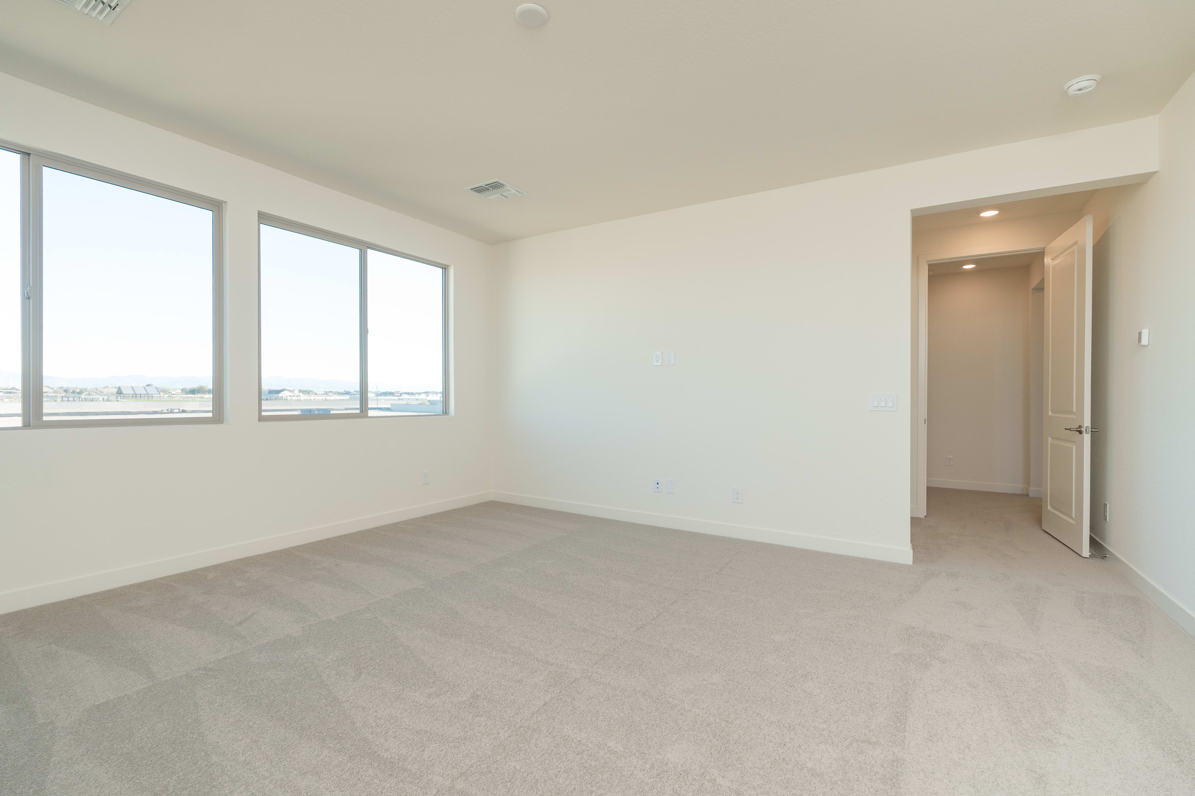 A spacious, well-lit room with large windows, a neutral color scheme, and a clean, minimalist design.