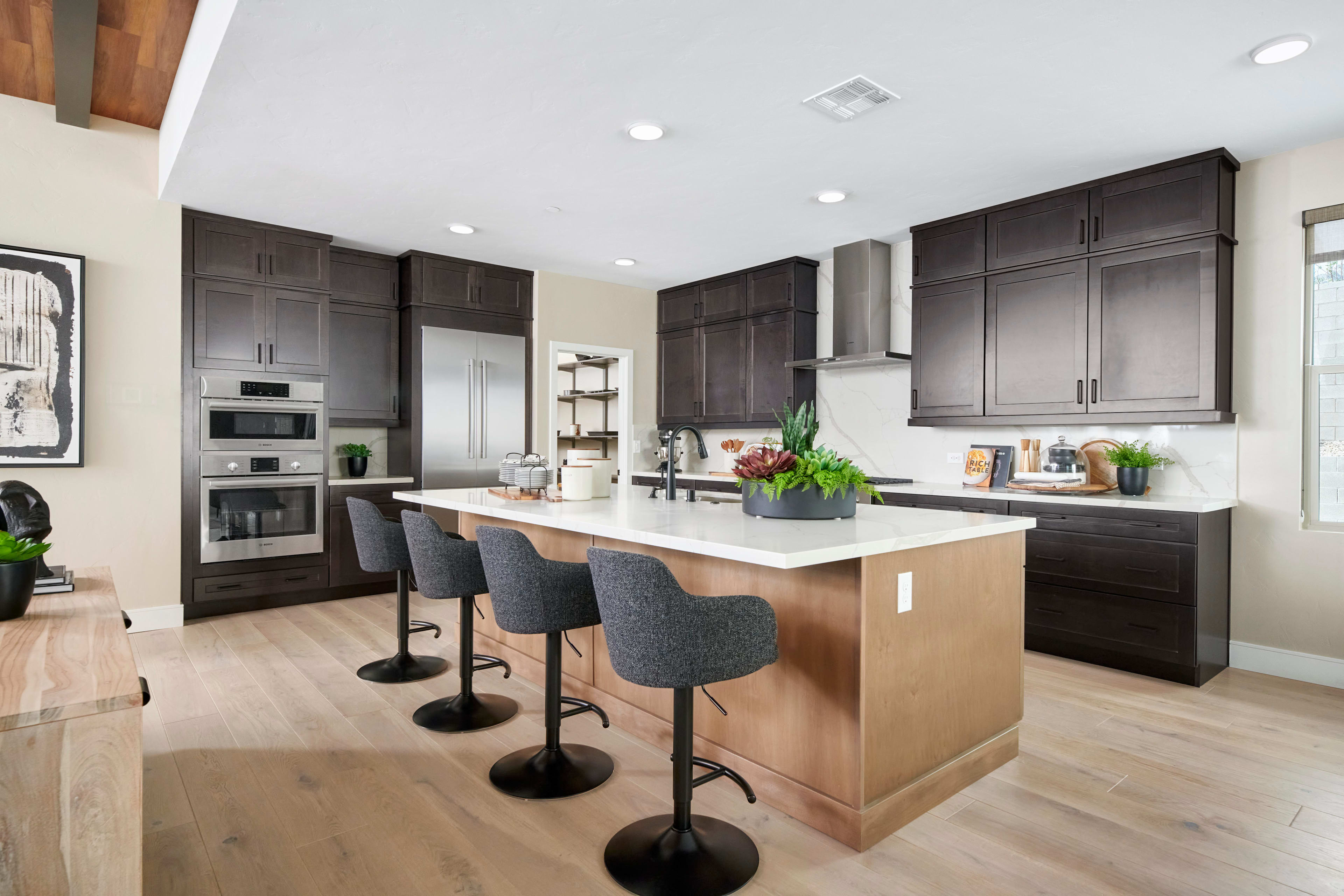 A modern and spacious kitchen with dark wood cabinets, a large island with bar stools, and stainless steel appliances.