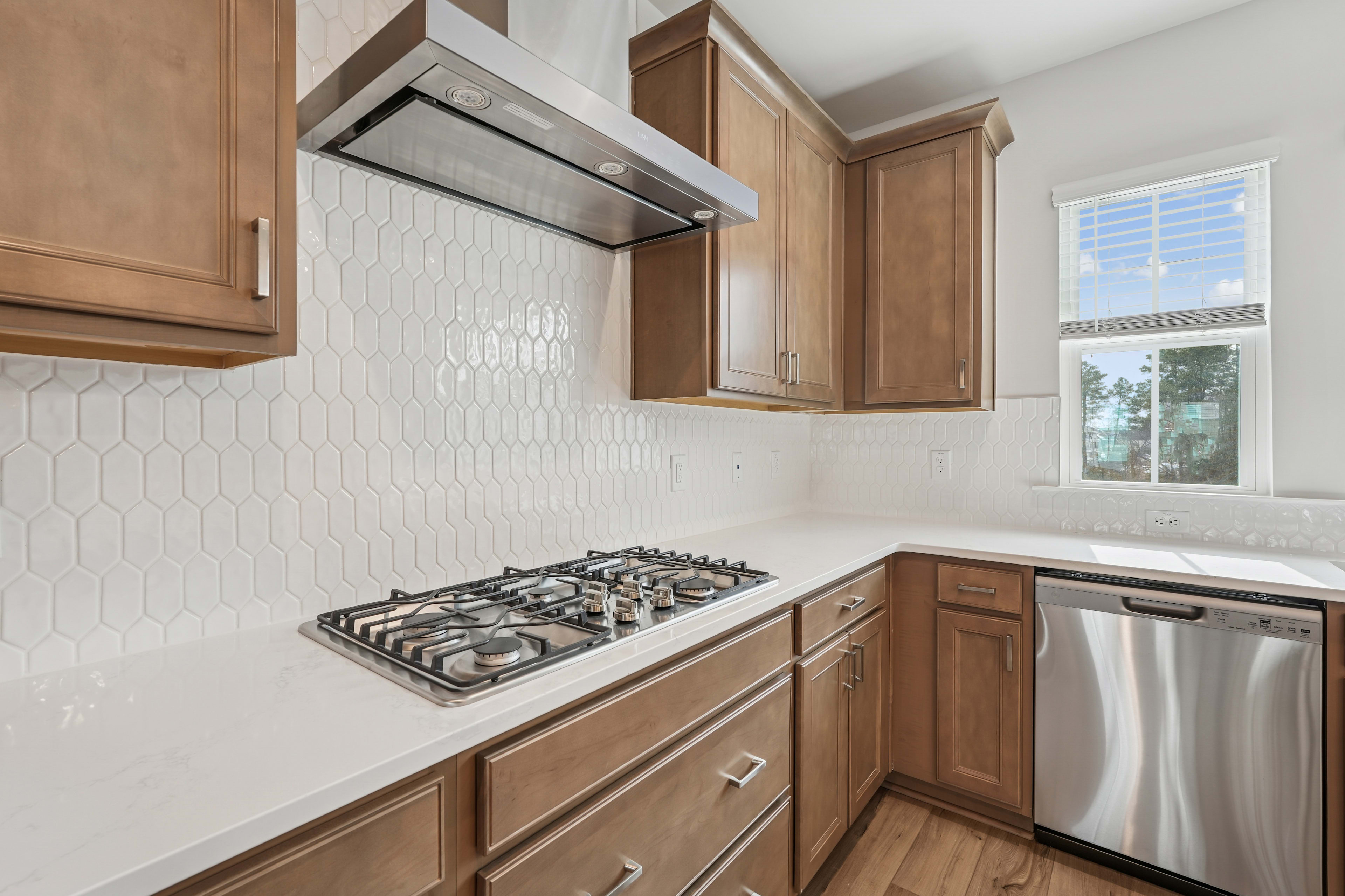 A modern kitchen with wooden cabinets, a gas stove, and a window providing natural light.