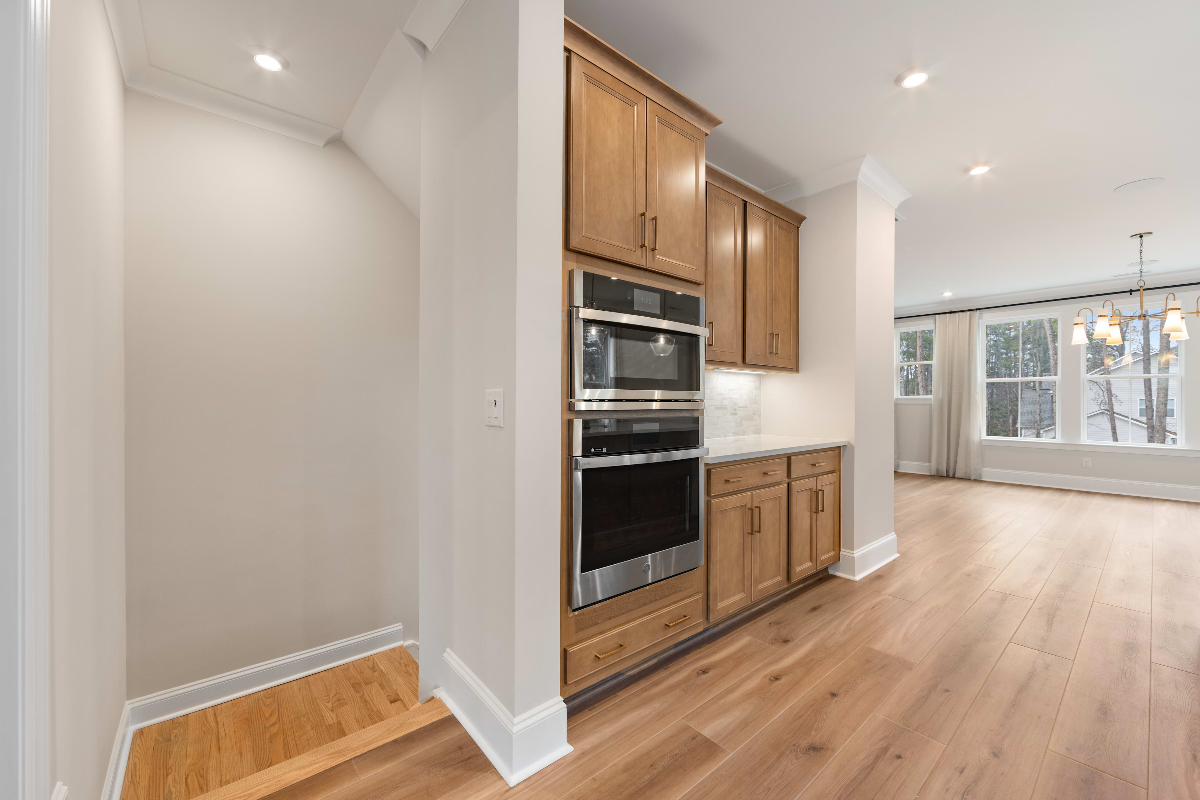 A modern kitchen with wooden cabinets, stainless steel appliances, and a hardwood floor, set against a bright and airy background.
