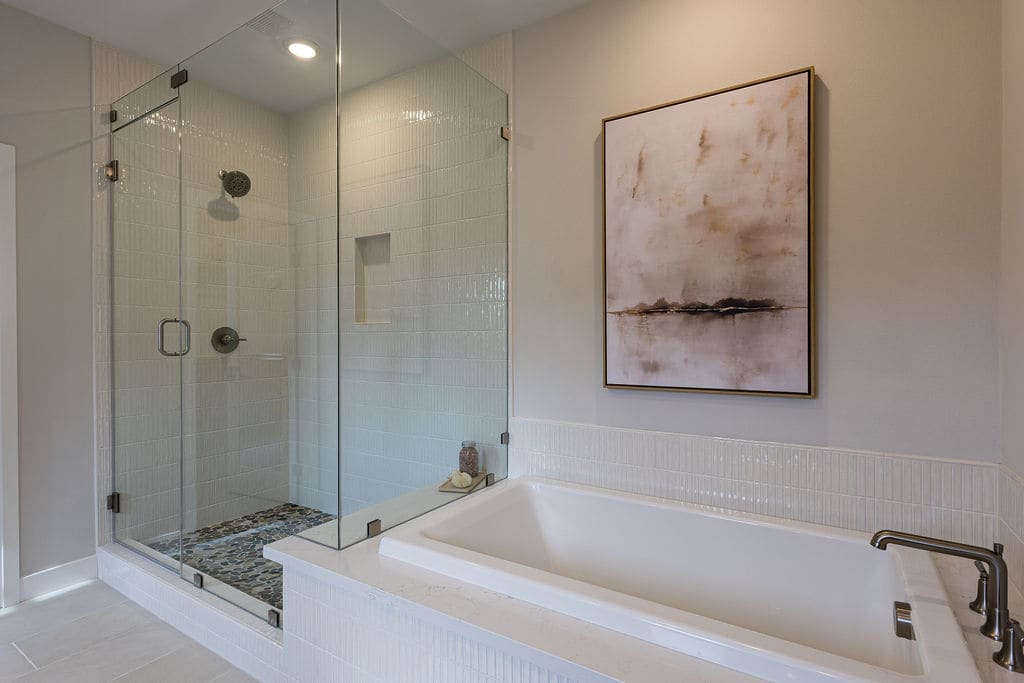 A modern bathroom with a large glass-enclosed shower, a freestanding bathtub, and a framed abstract artwork on the wall.