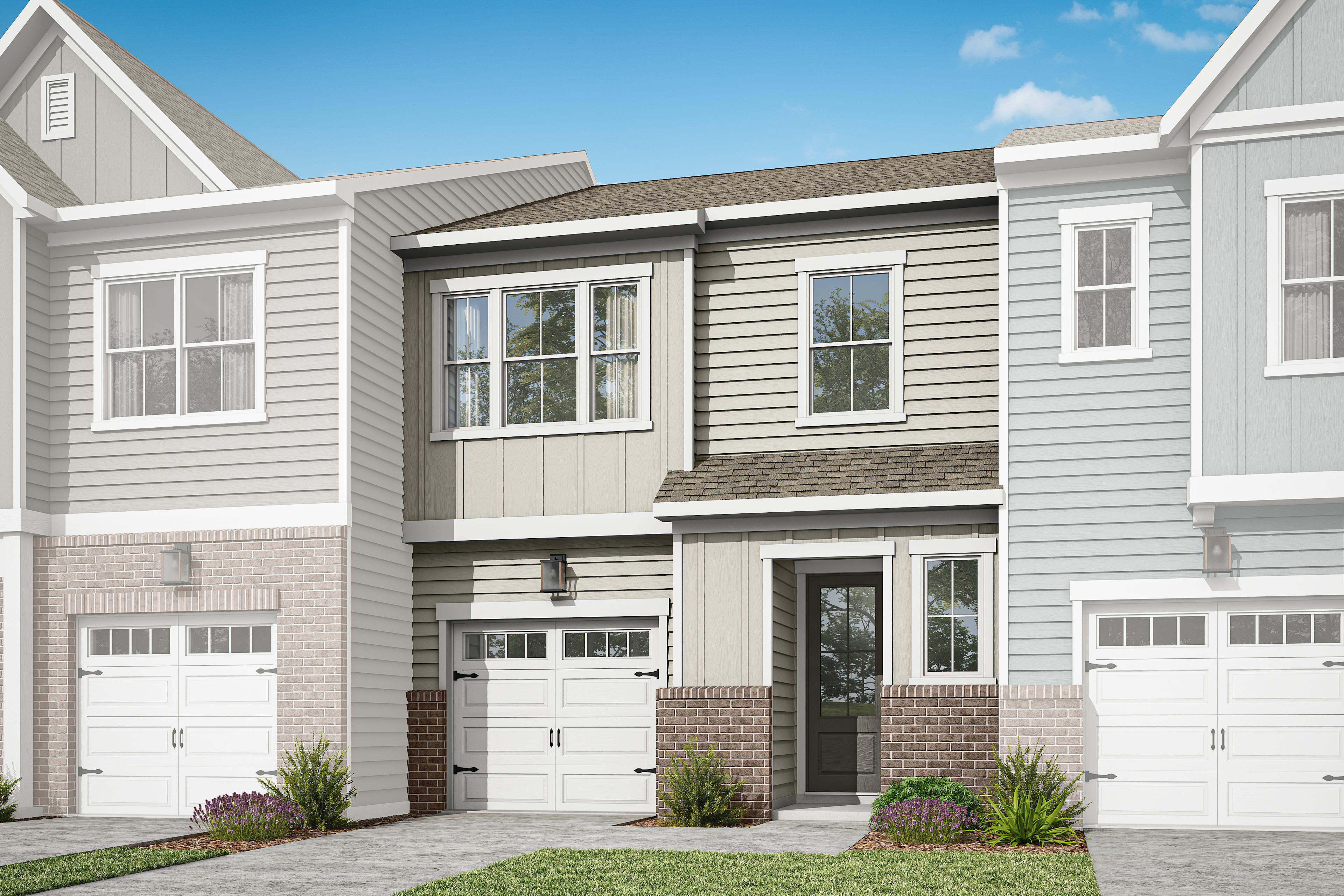 A two-story townhouse with a gray exterior, white trim, and a brick foundation sits in a grassy area with a clear blue sky in the background.