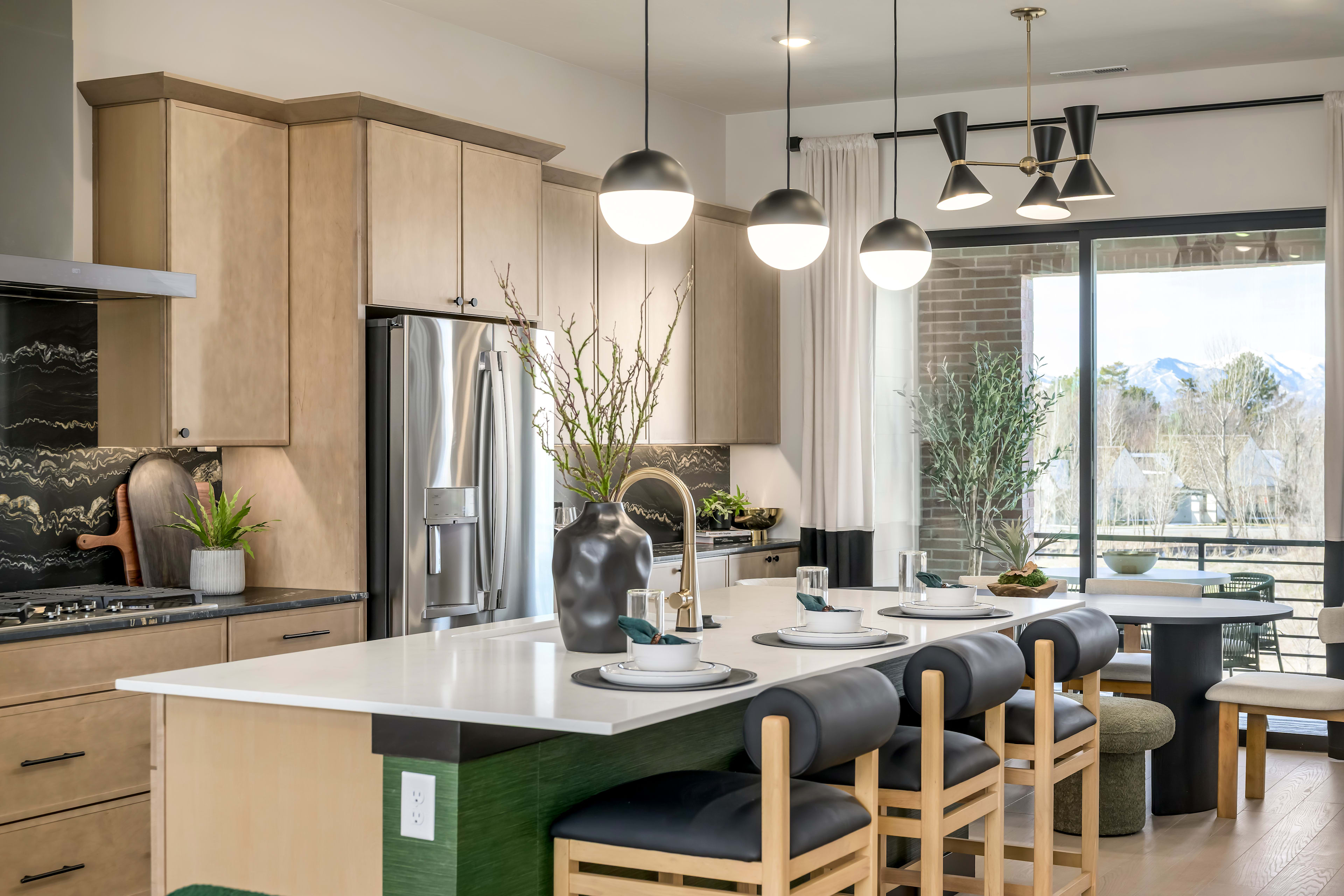 A modern and well-designed kitchen with a large island, pendant lights, and a view of the outdoors through a window.