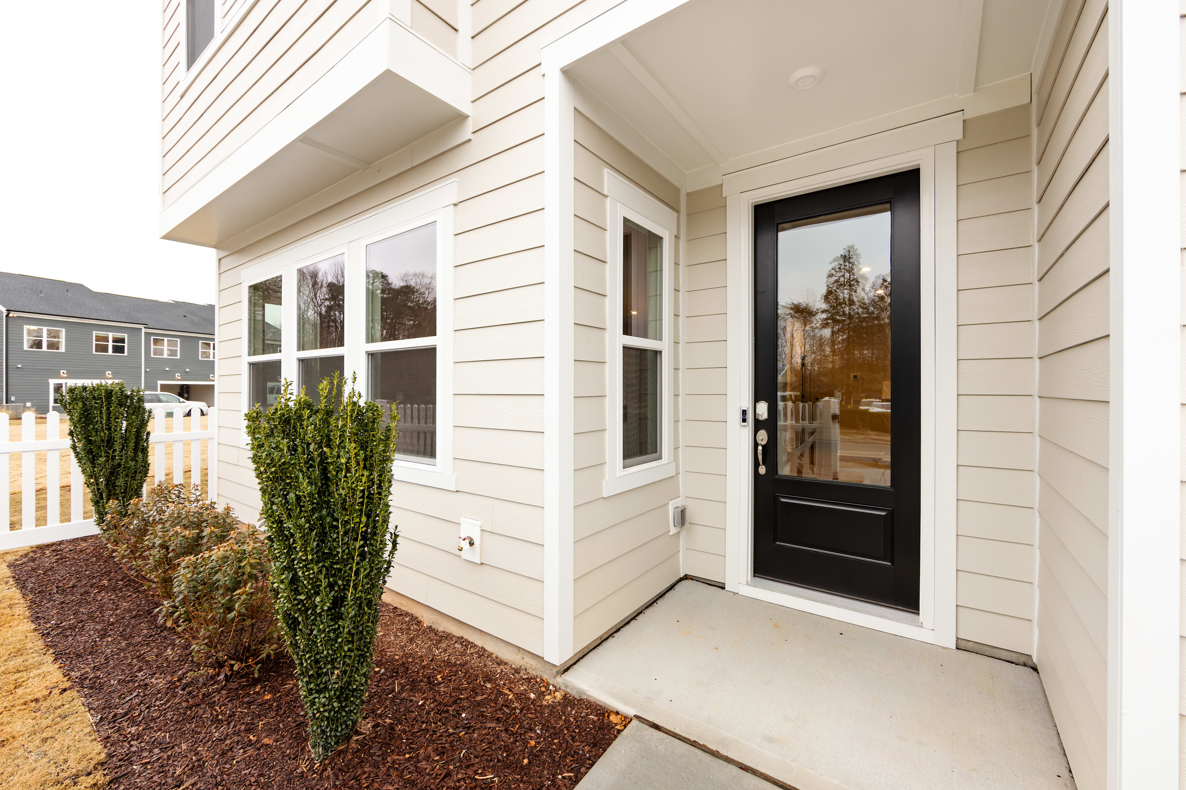 A well-maintained residential home with a porch, surrounded by landscaped greenery and a paved walkway leading to the front door.