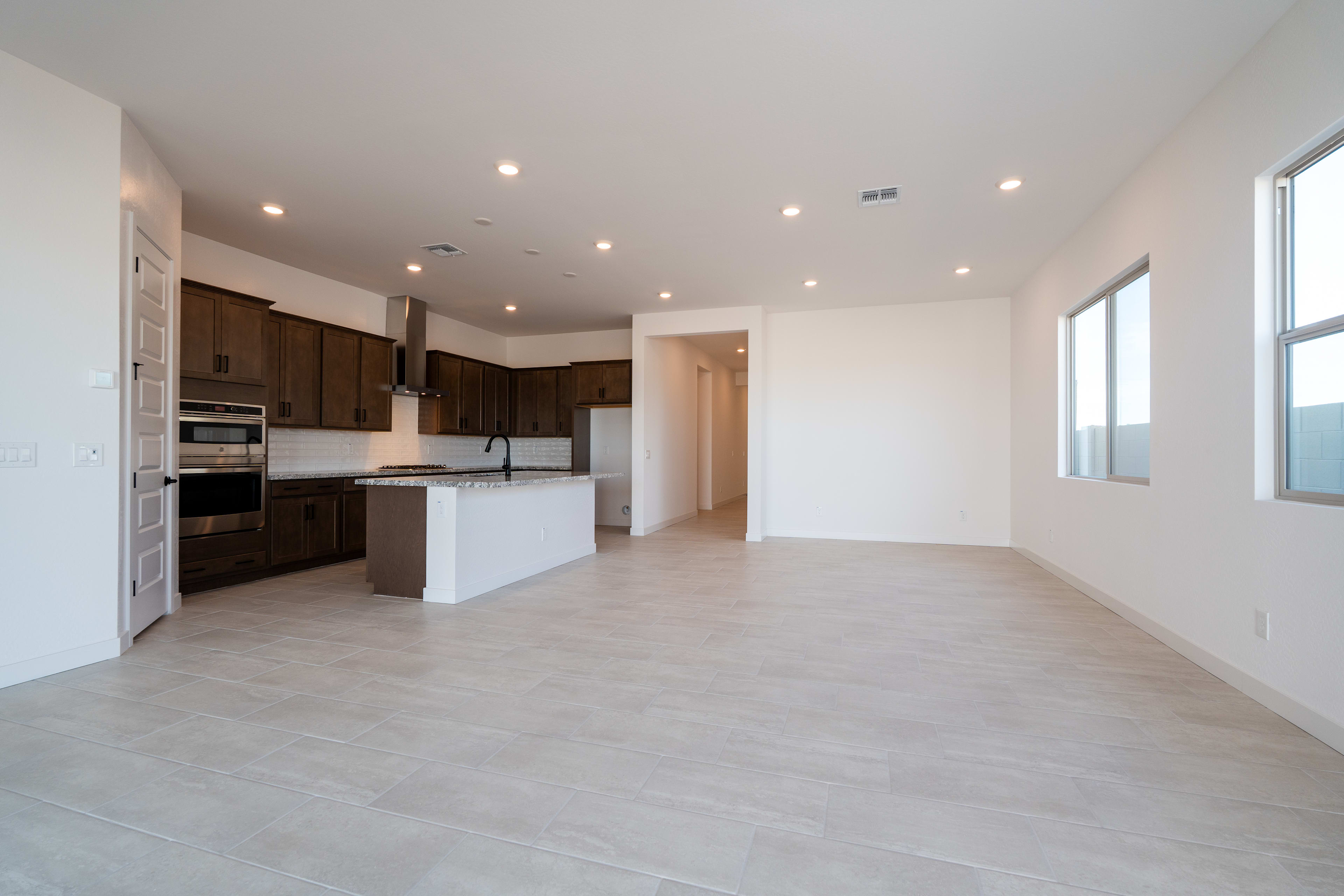 A spacious, open-concept kitchen and living area with modern appliances, dark wood cabinets, and light-colored flooring.