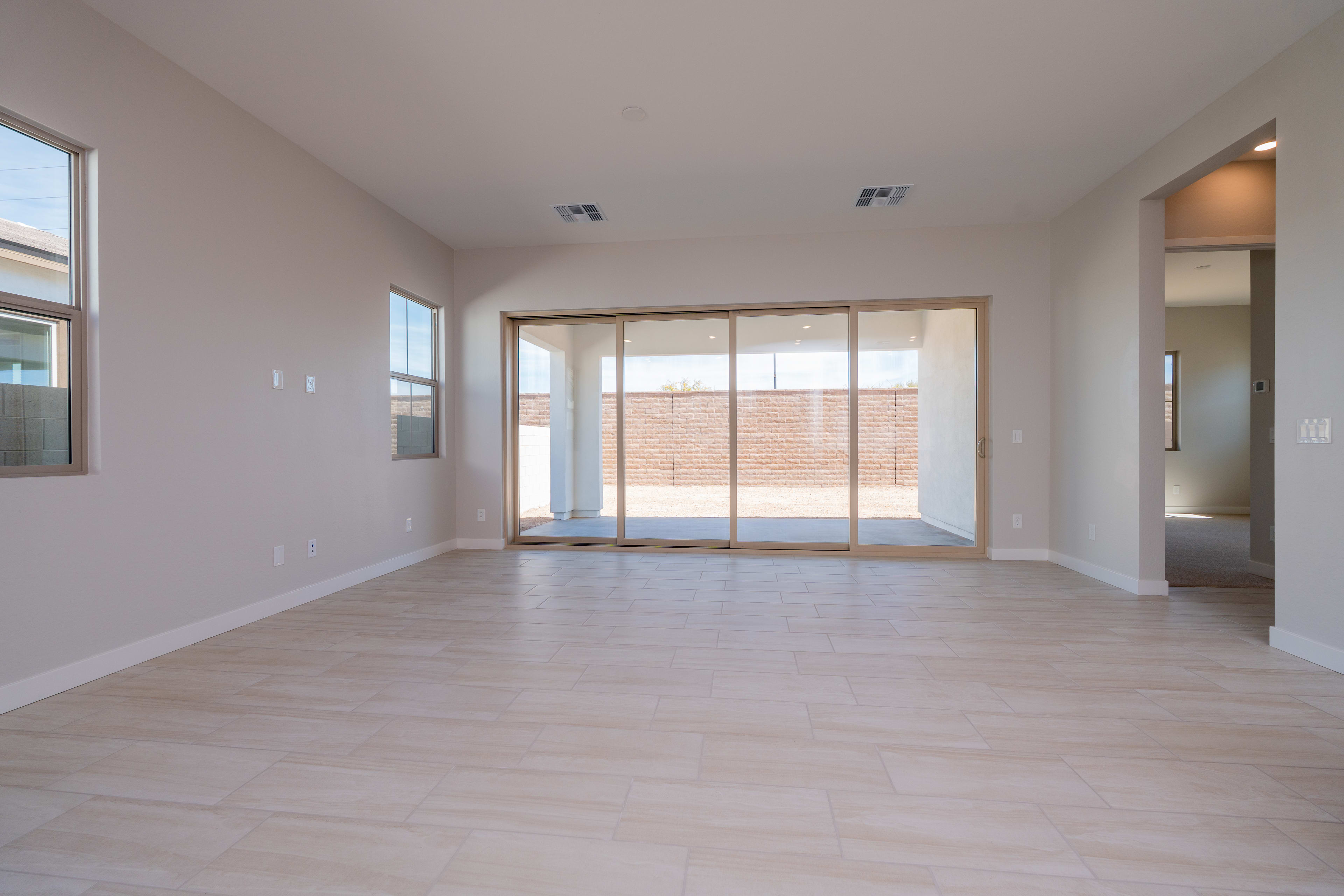 A spacious, minimalist living room with large windows, hardwood floors, and a clean, modern aesthetic.