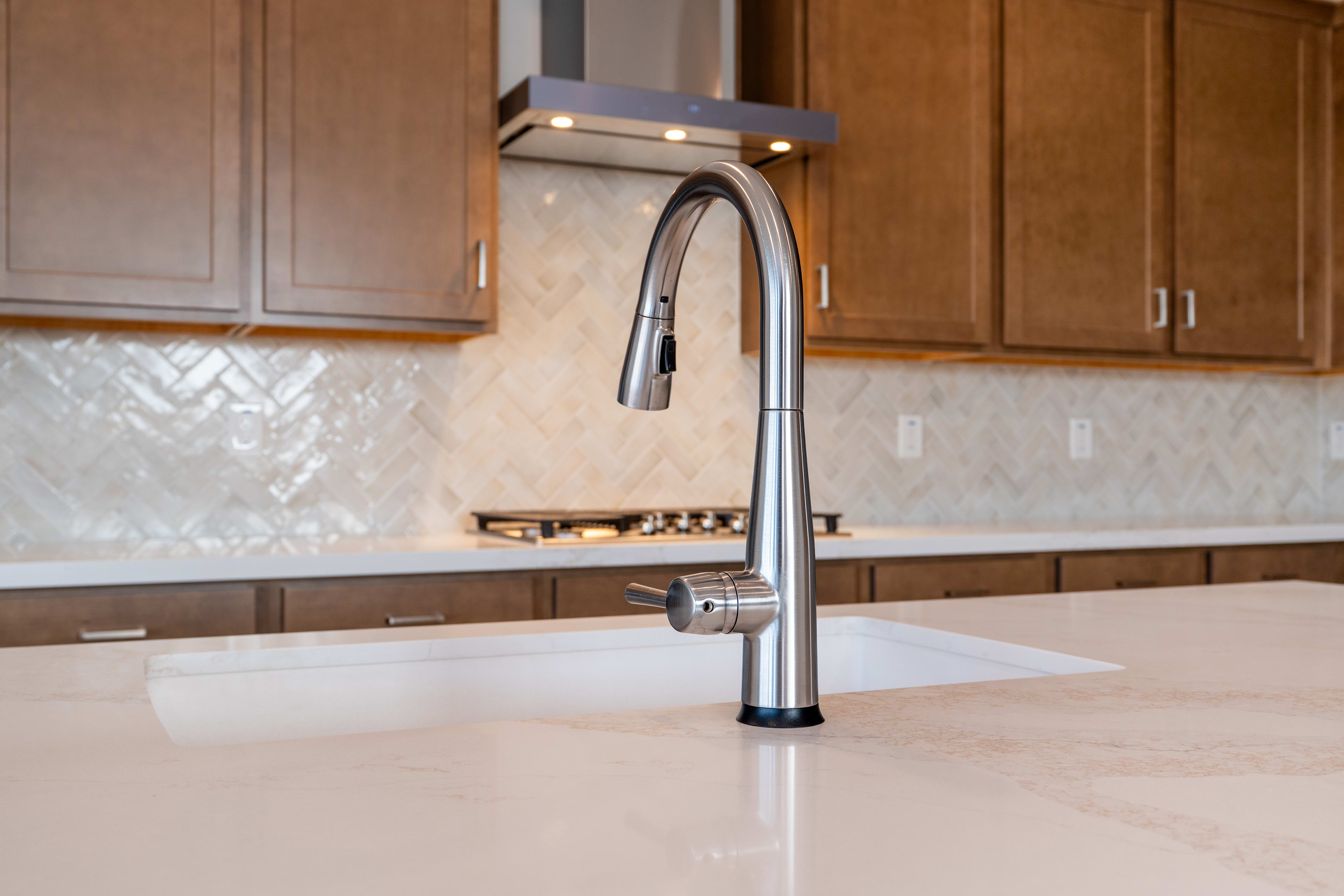 A modern kitchen with wooden cabinets, a chrome faucet, and a white countertop.