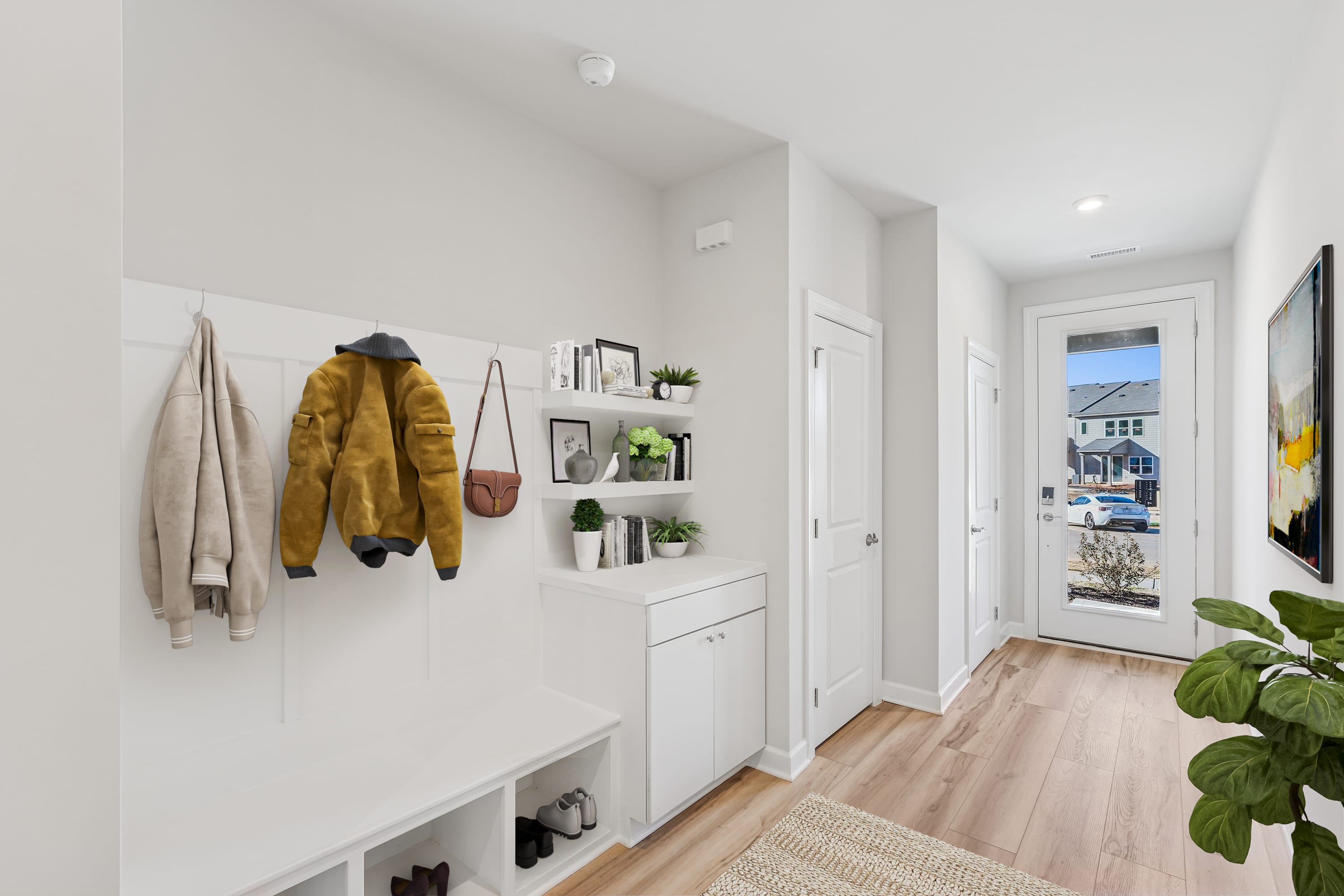 A bright and minimalist entryway with a white wall, wooden floors, and shelves displaying decorative items and a yellow jacket.