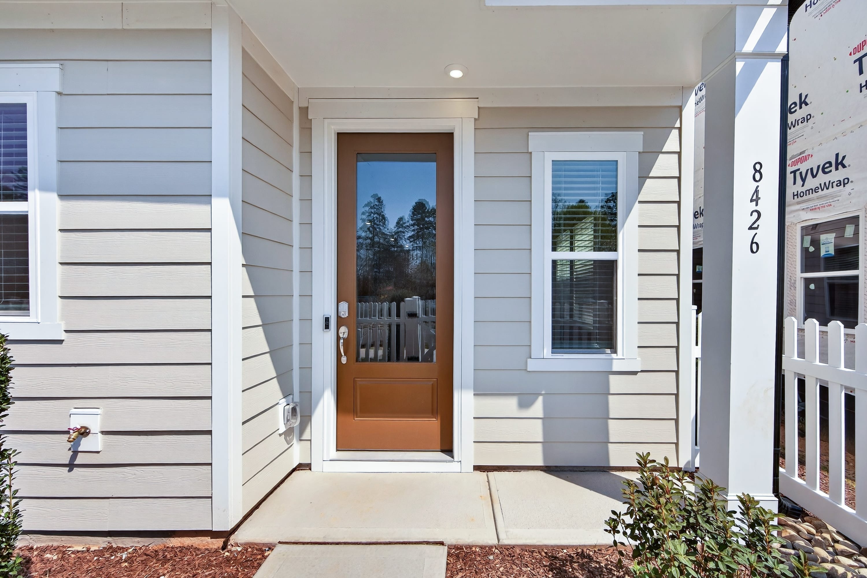 A well-maintained, modern-style home with a wooden front door, surrounded by a paved walkway and landscaping.