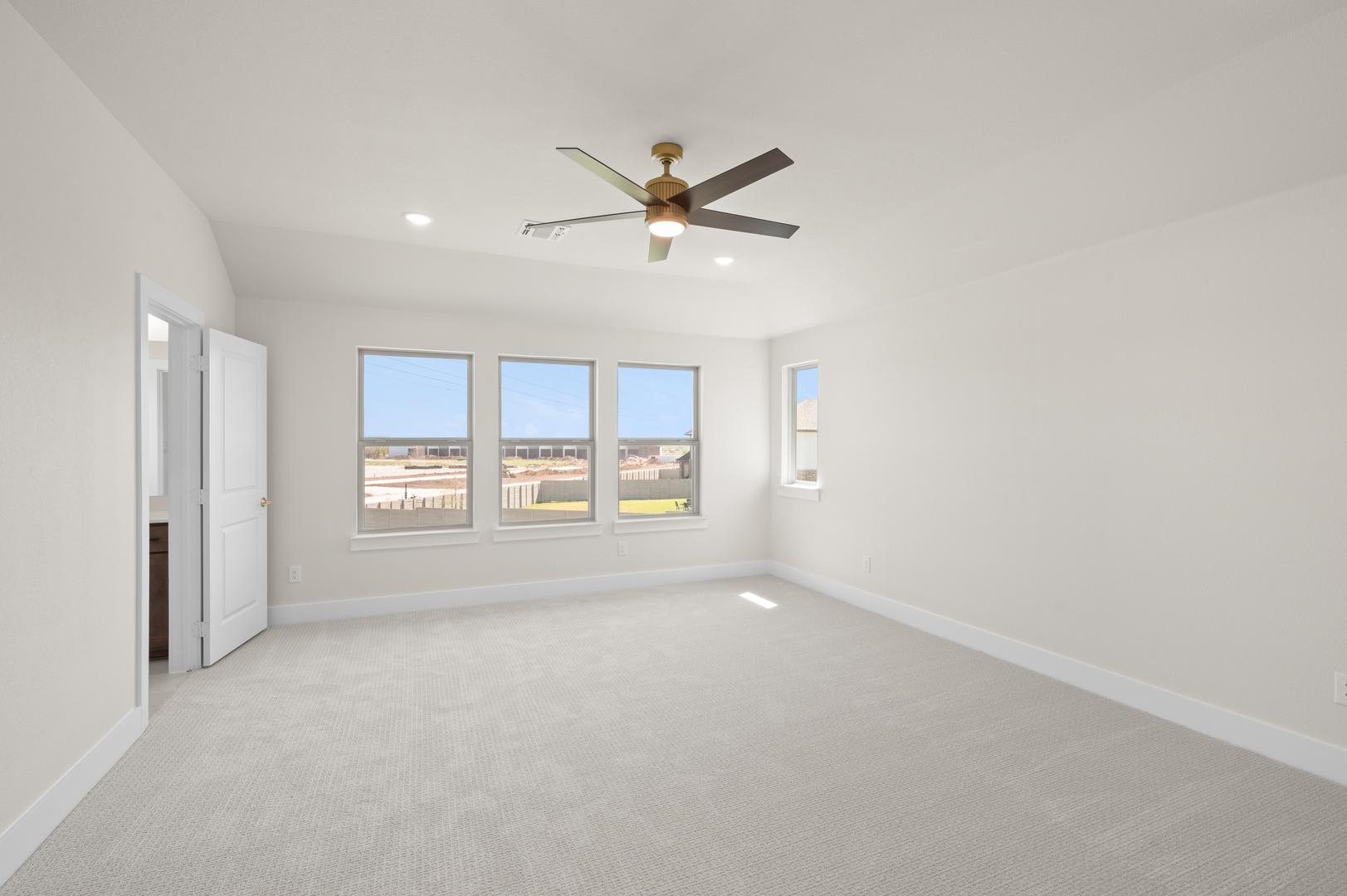 A spacious, well-lit room with a ceiling fan and large windows overlooking an outdoor area.