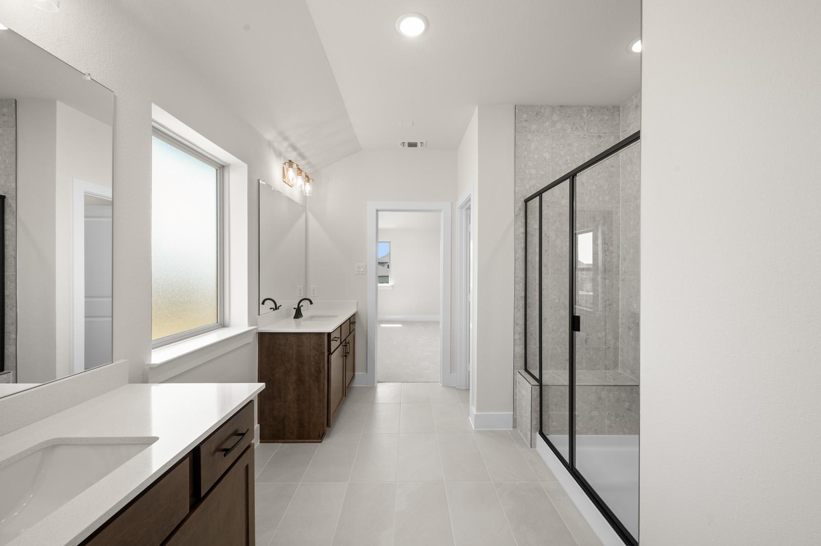 A modern, minimalist bathroom with a wooden vanity, a large mirror, and a glass-enclosed shower area, set against a bright, airy backdrop.