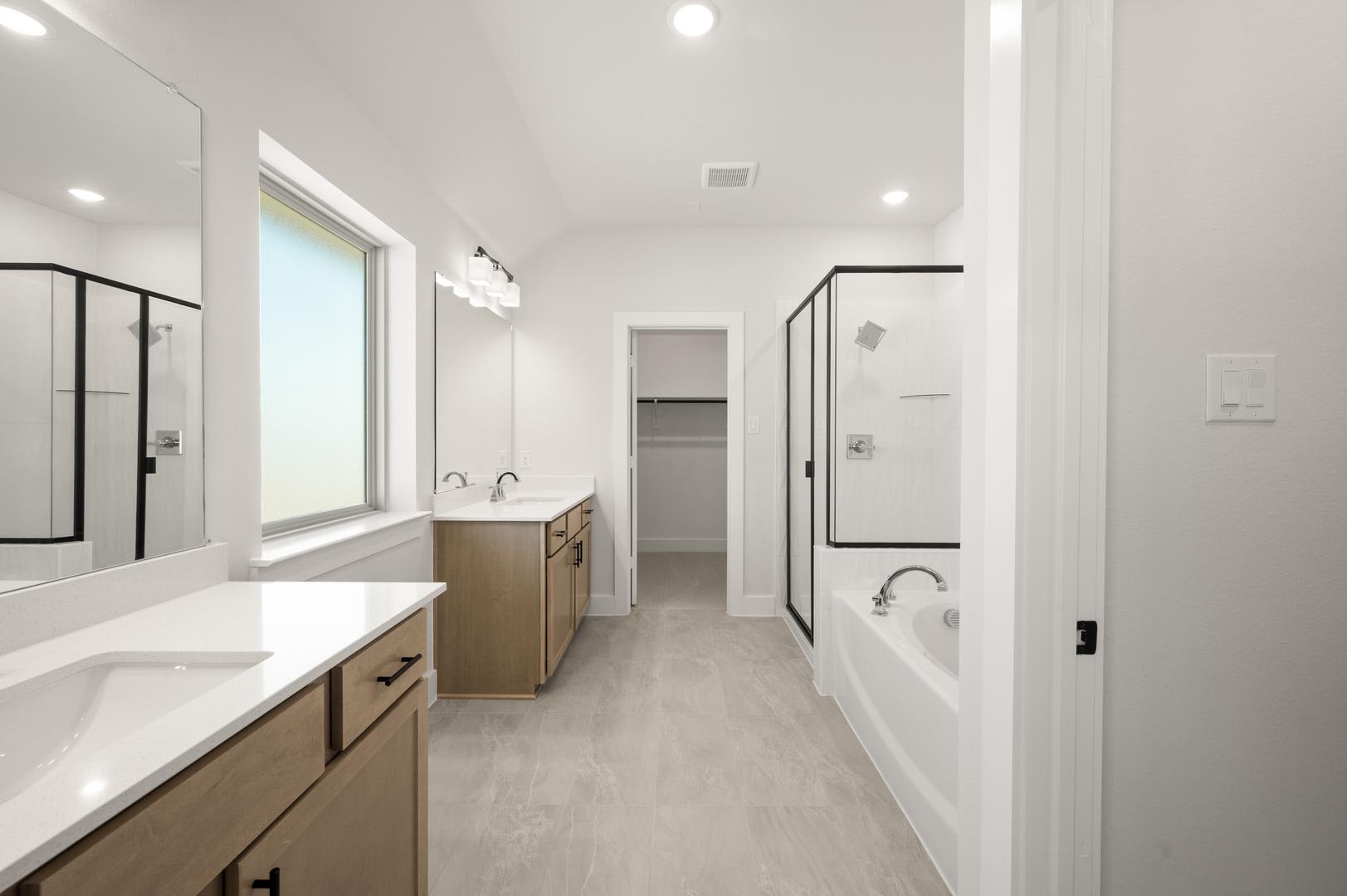 A modern, minimalist bathroom with a long vanity, double sinks, and a large window providing natural light, creating a bright and airy atmosphere.