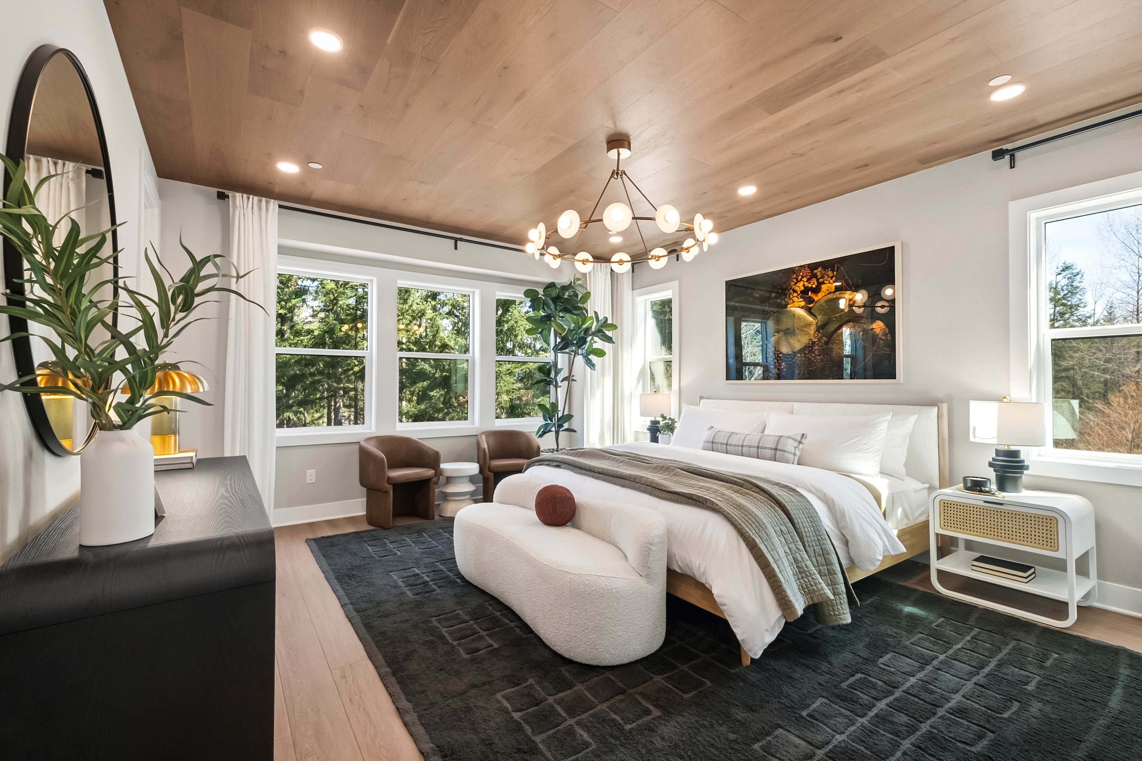 A spacious and elegantly designed bedroom with large windows, a plush bed, and various decorative elements, creating a cozy and inviting atmosphere.