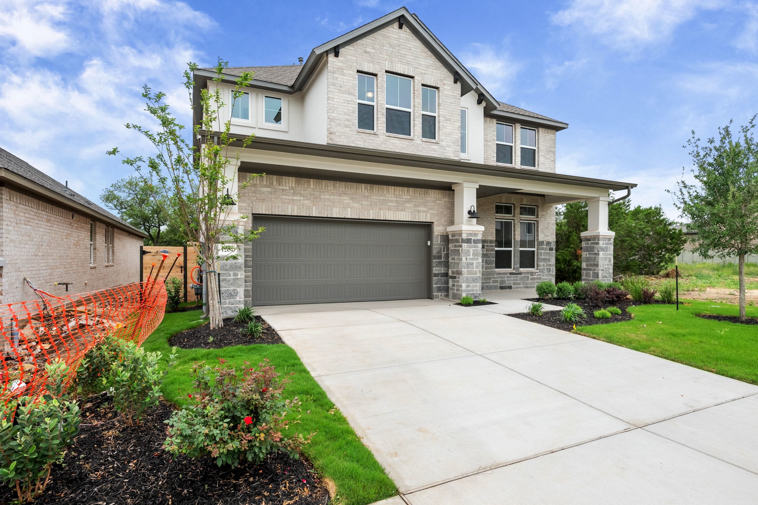 A modern two-story house with a gray exterior, a garage, and a well-maintained lawn and landscaping in the foreground.